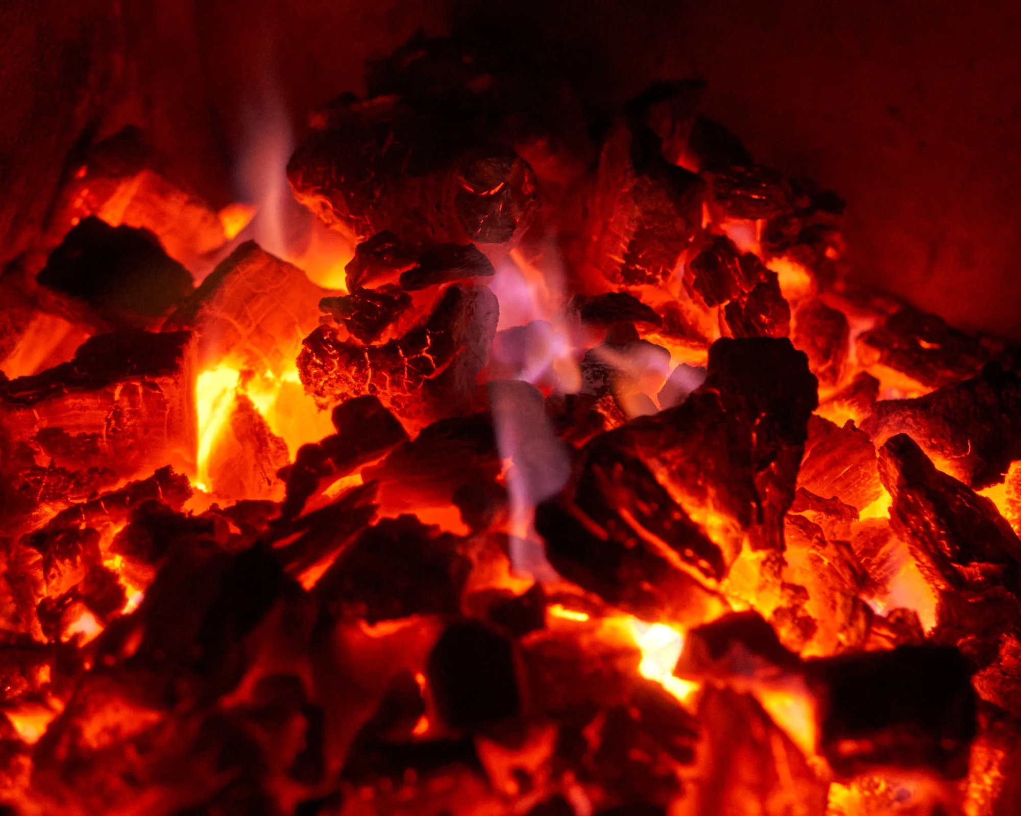 Carbón ardiente con llamas y brasas rojas y negras.