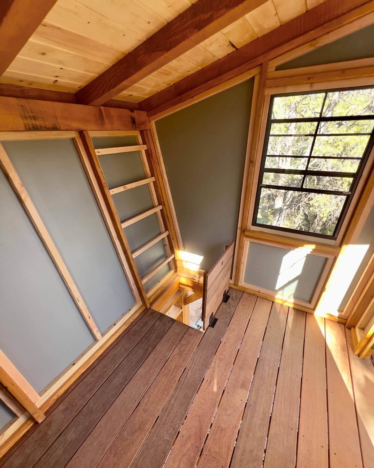 Interior of the Fort David Playhouse, featuring trap door access to the deck below, integrated chalk board wall, custom tree-lite door, and operable windows with screens!