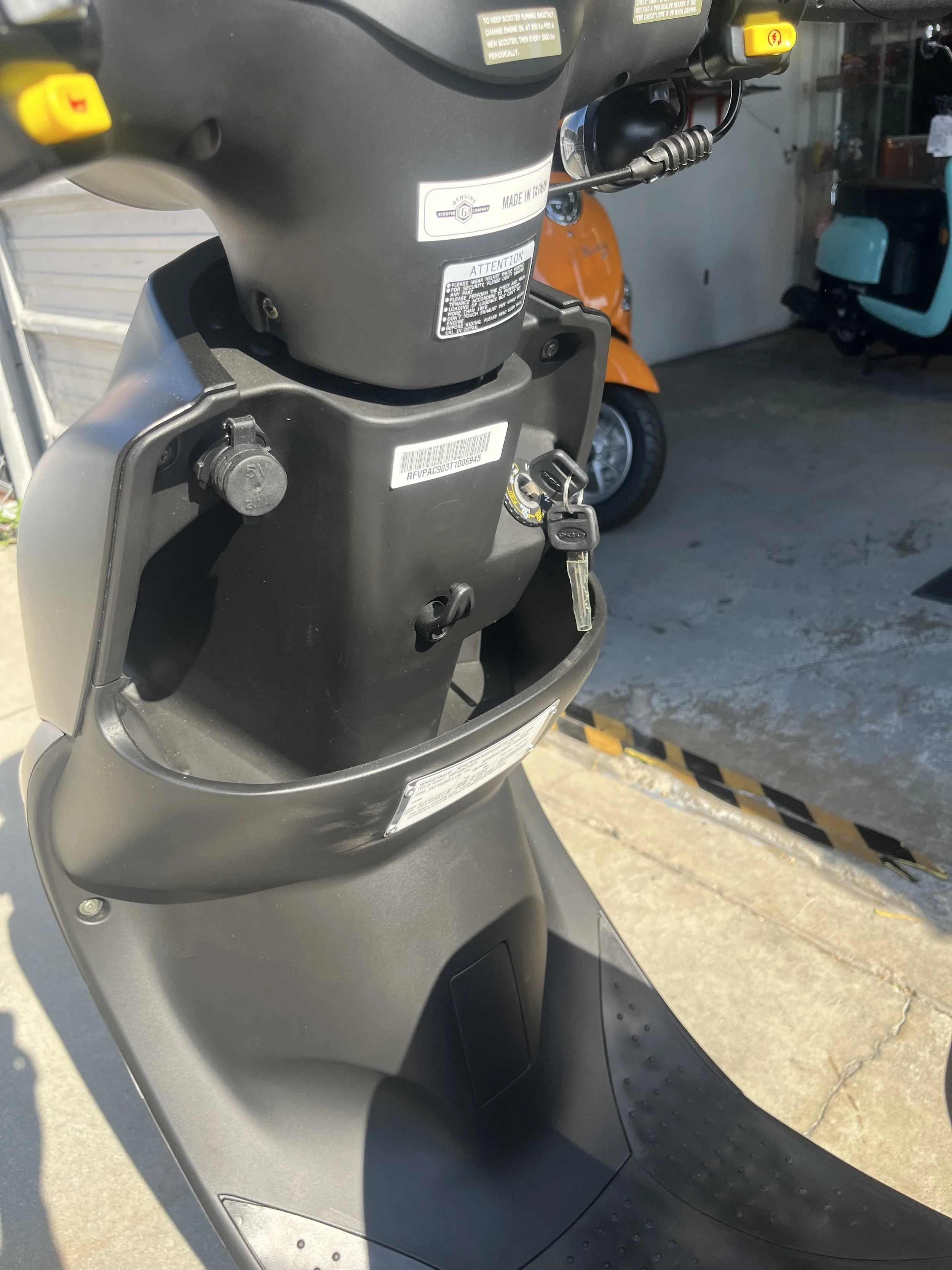 Close-up of the dashboard and ignition area of a scooter, with keys inserted in the ignition.