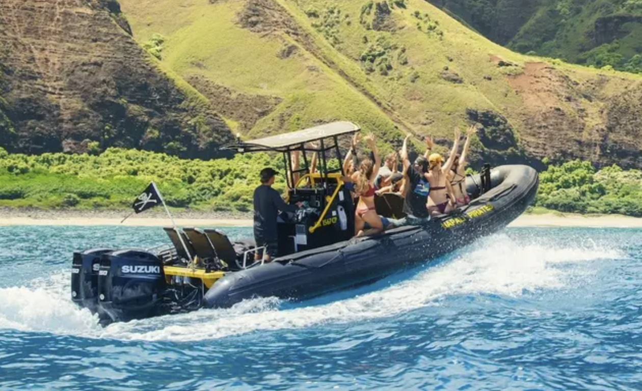 People enjoying a speedboat ride on a body of water with green hills in the background.