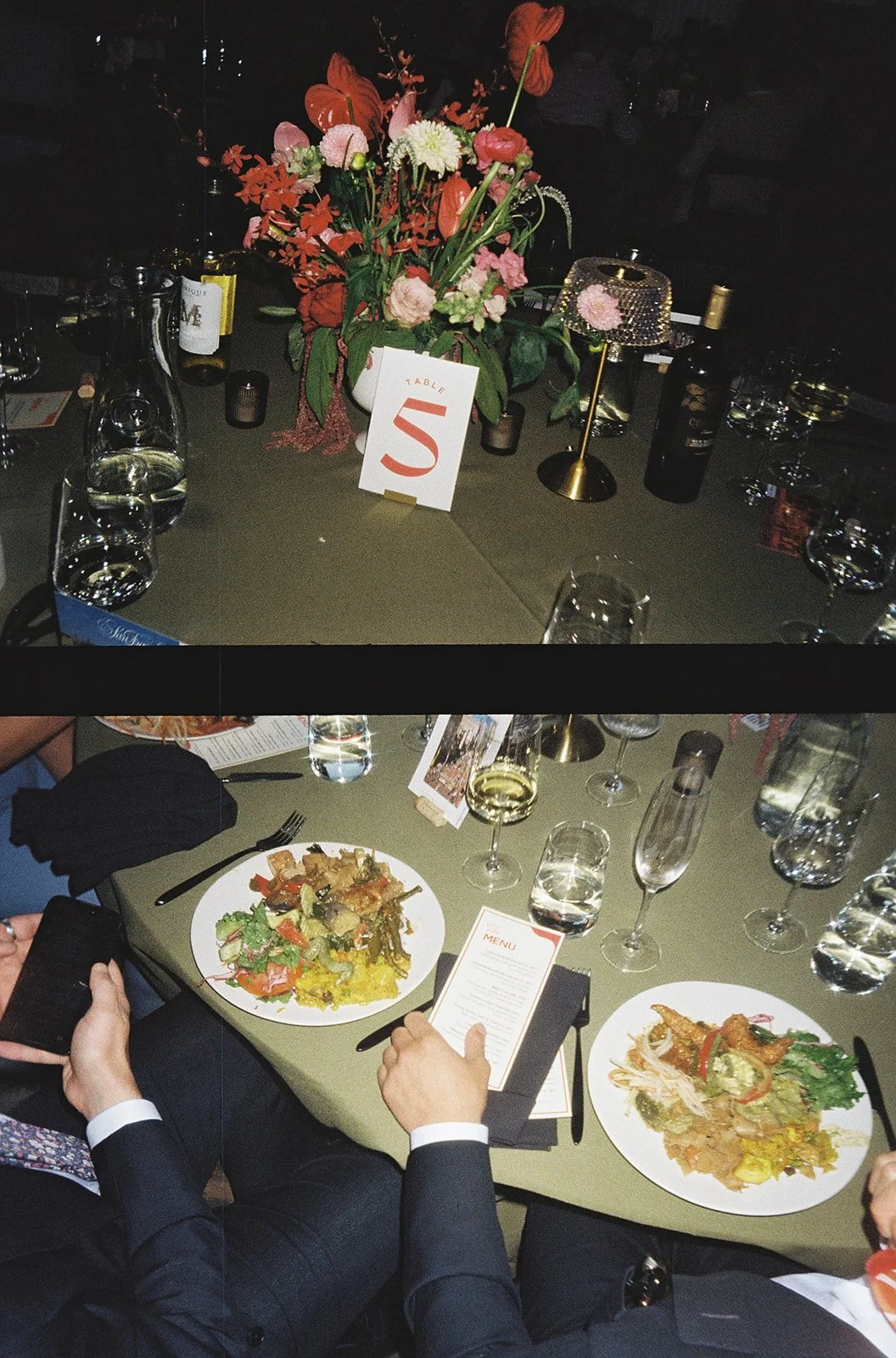 A dinner table setting with a floral centerpiece, wine glasses, bottles, and a table number card. The lower part of the image shows people dining, with plates of food, glasses, and menus on the table.