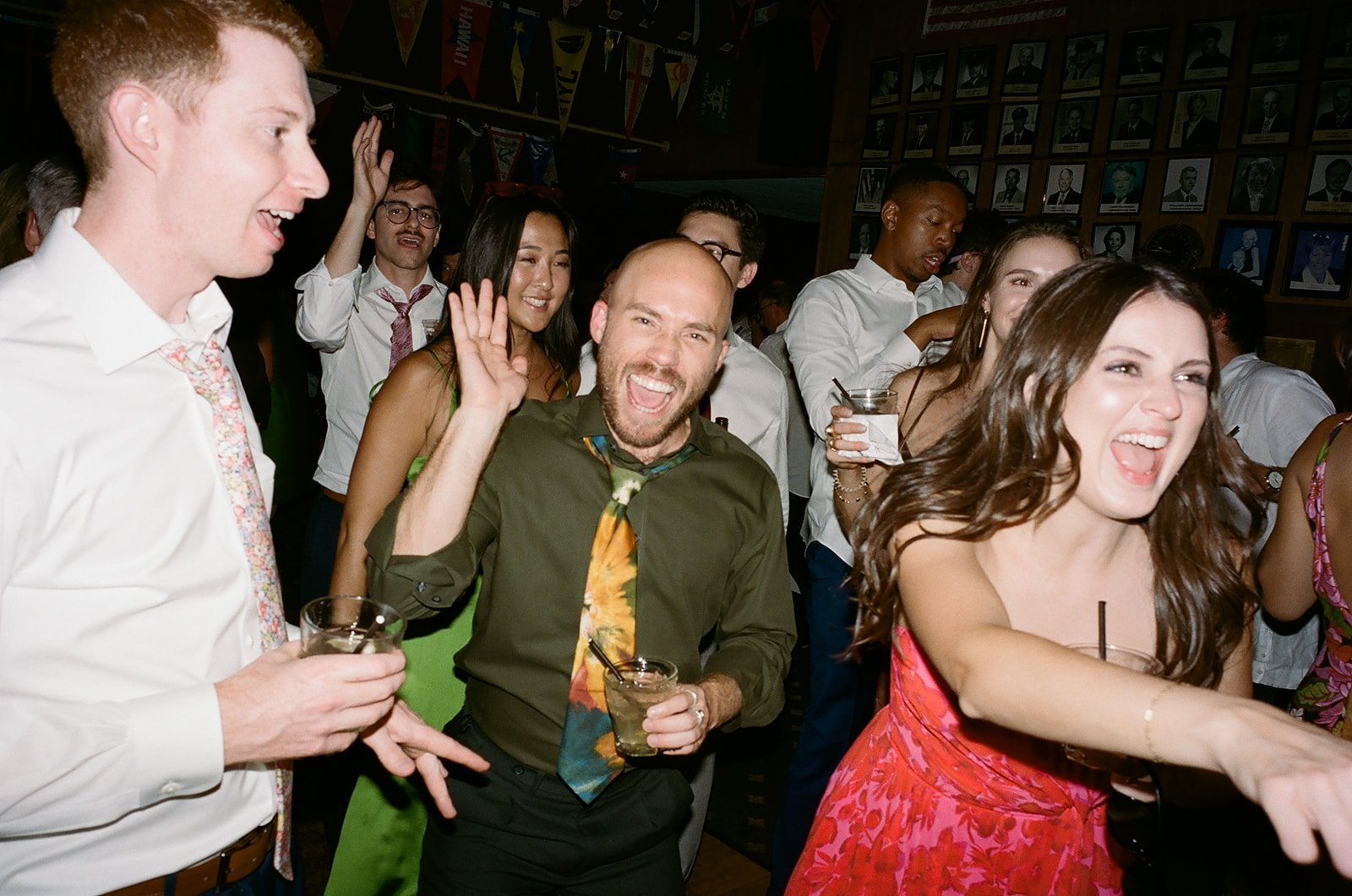 Group of people at a party dancing and enjoying drinks, smiling and having fun.