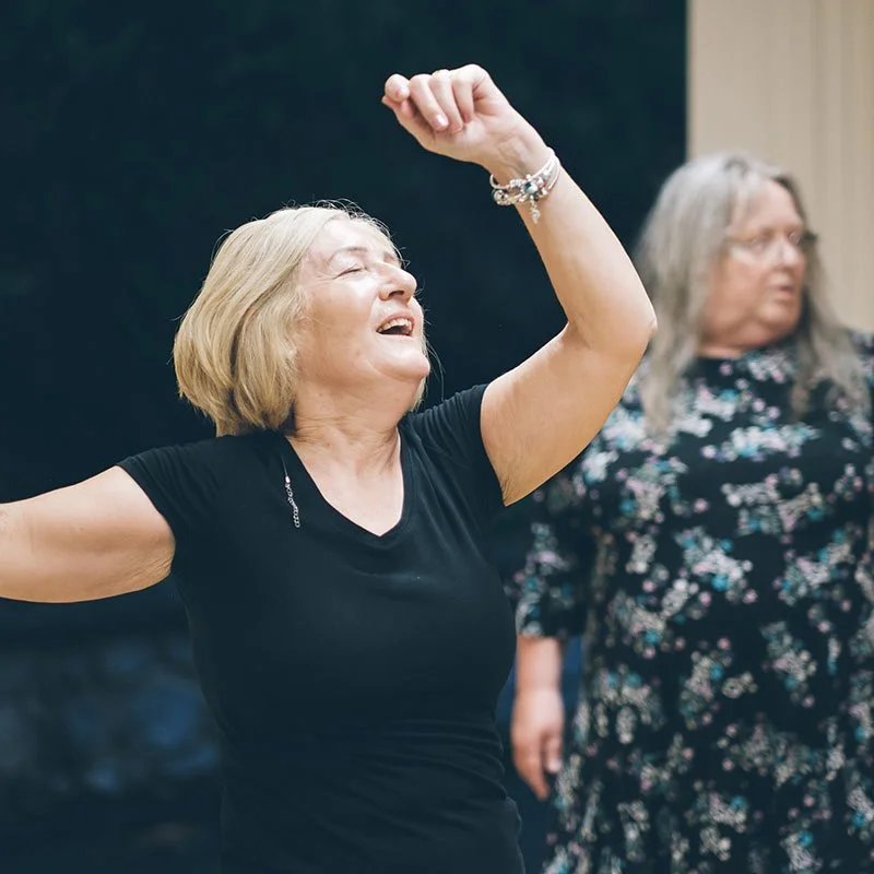 A woman smiling and dancing with arms raised during a Groove track.