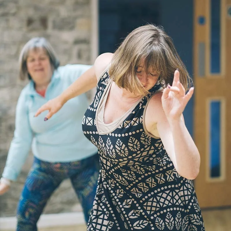 Two women dancing energetically and having fun during a Groove session.
