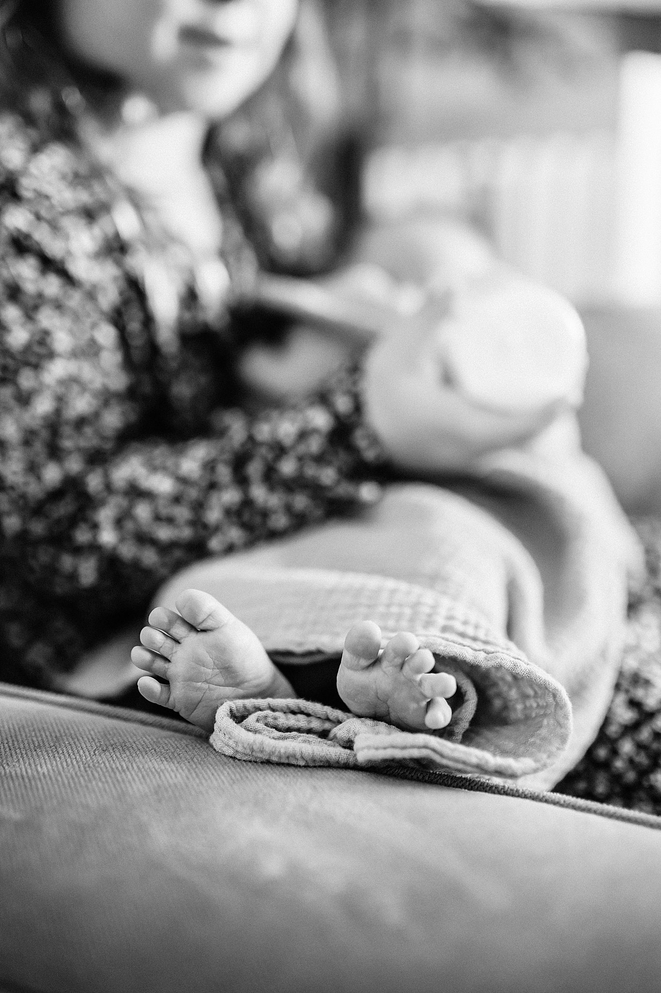 Close up black and white image of a toddler girl feeding her new baby brother.
