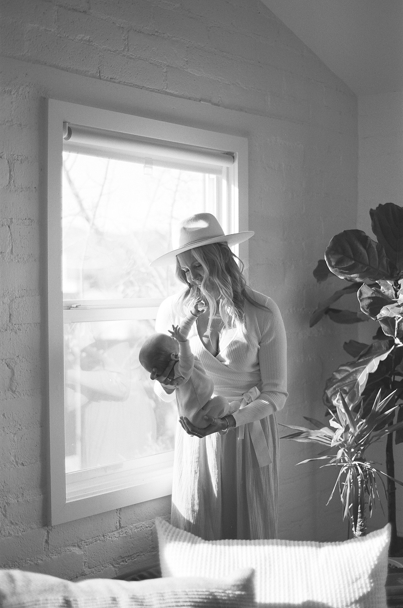 A mom in a boho outfit holding her newborn in a black and white film portrait taken by Alyssa Charbonea Photography.
