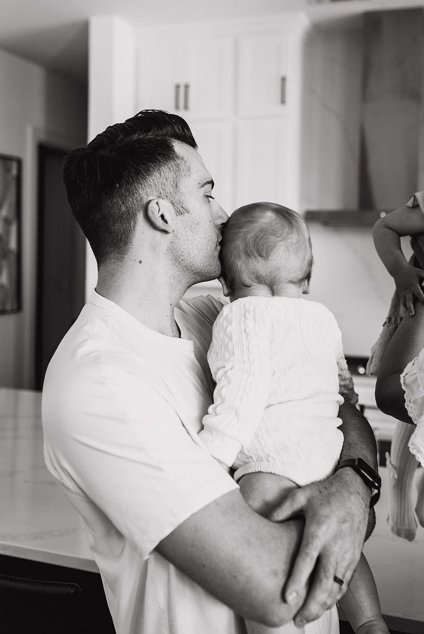 A dad snuggling his six-month old baby during an in-home family session.