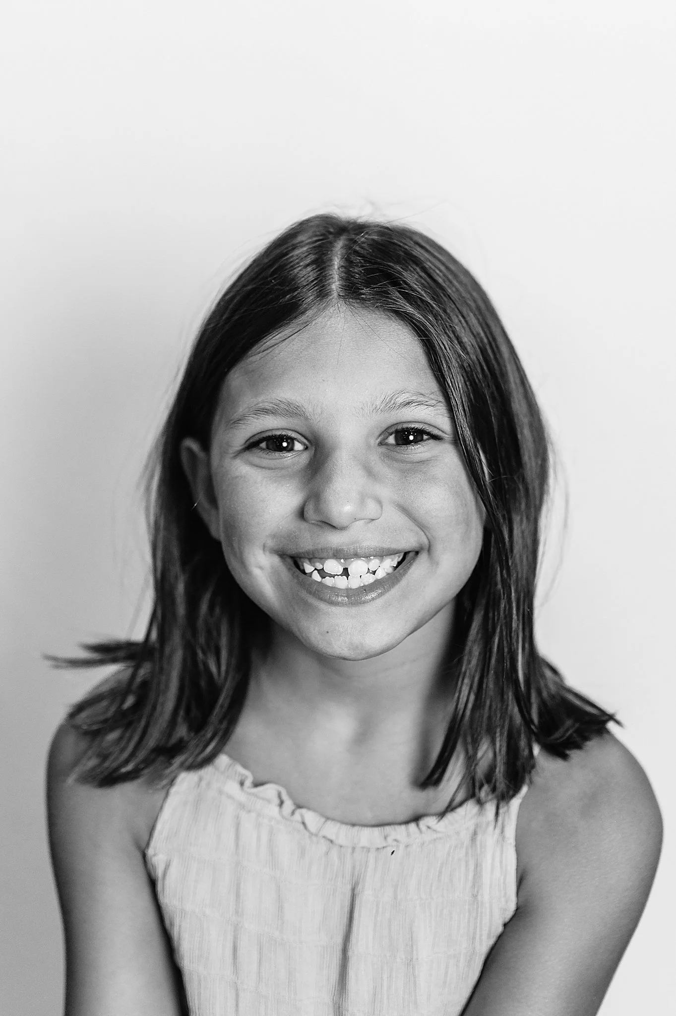 black and white image of a 4th grade girl smiling for her school portraits.