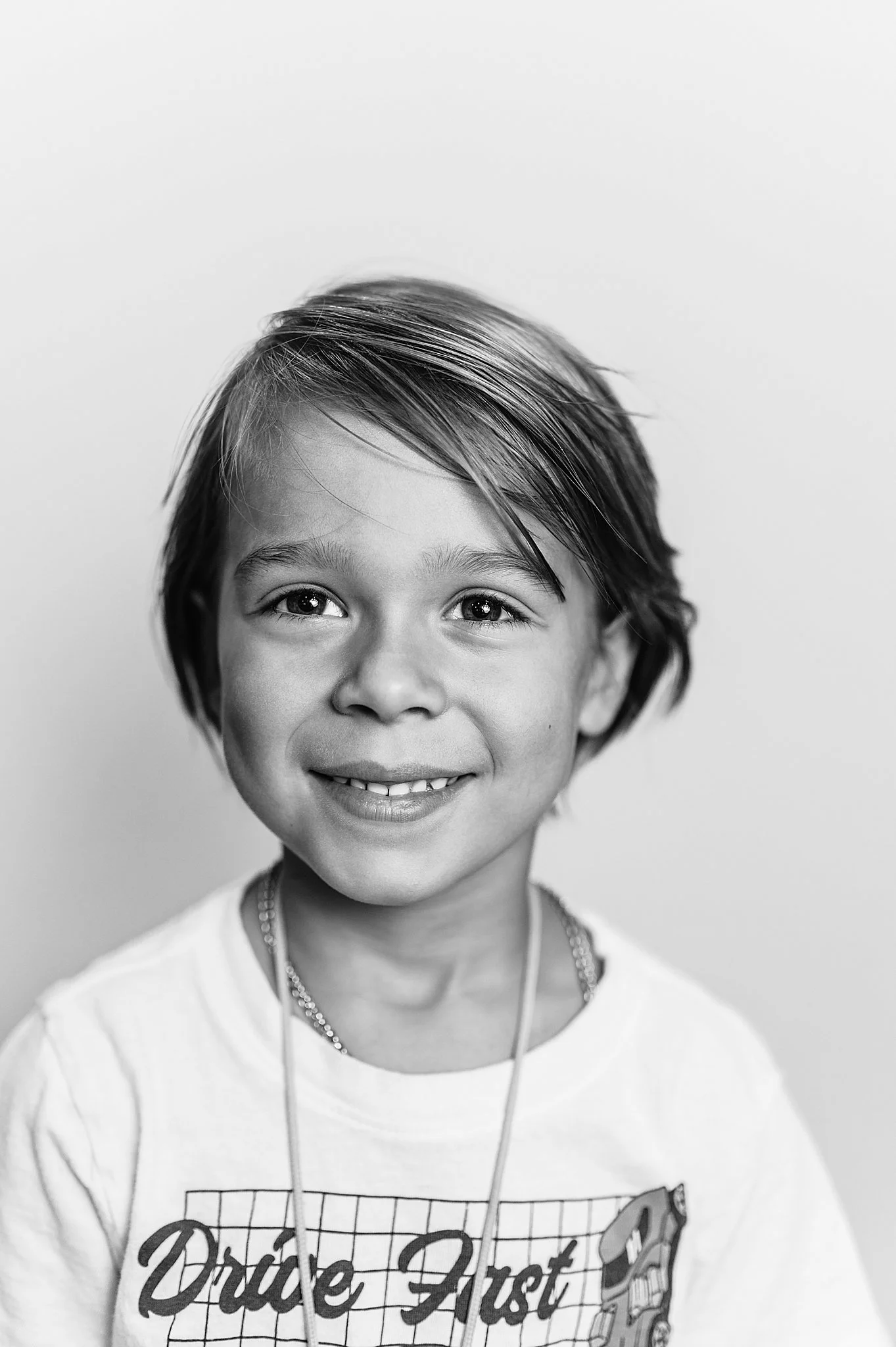 Black and white image of a fine art school portrait, 6 year old boy with longer hair.