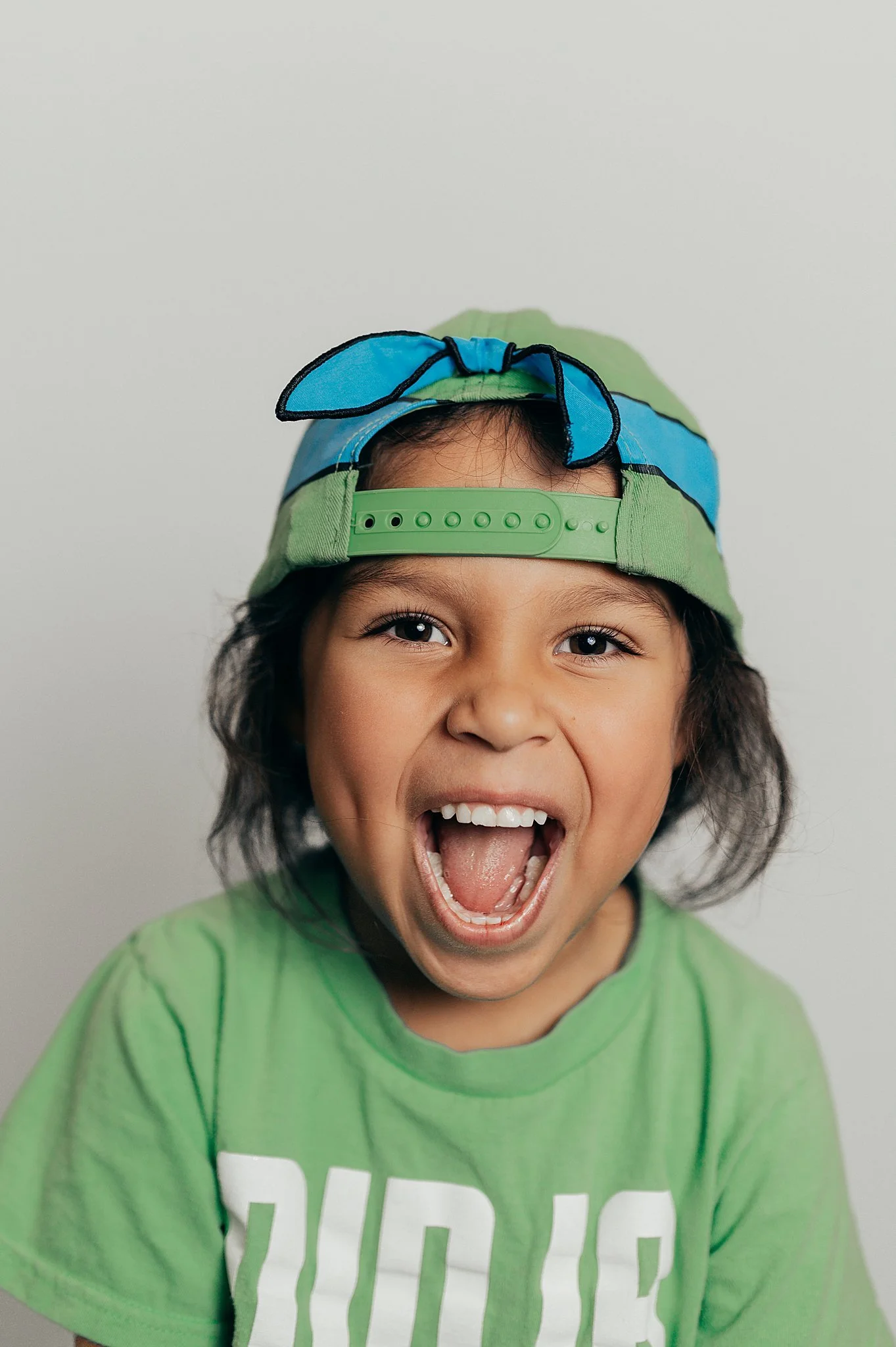 1st grade girl in a ninja turtle hat at her Las Vegas school portrait session.