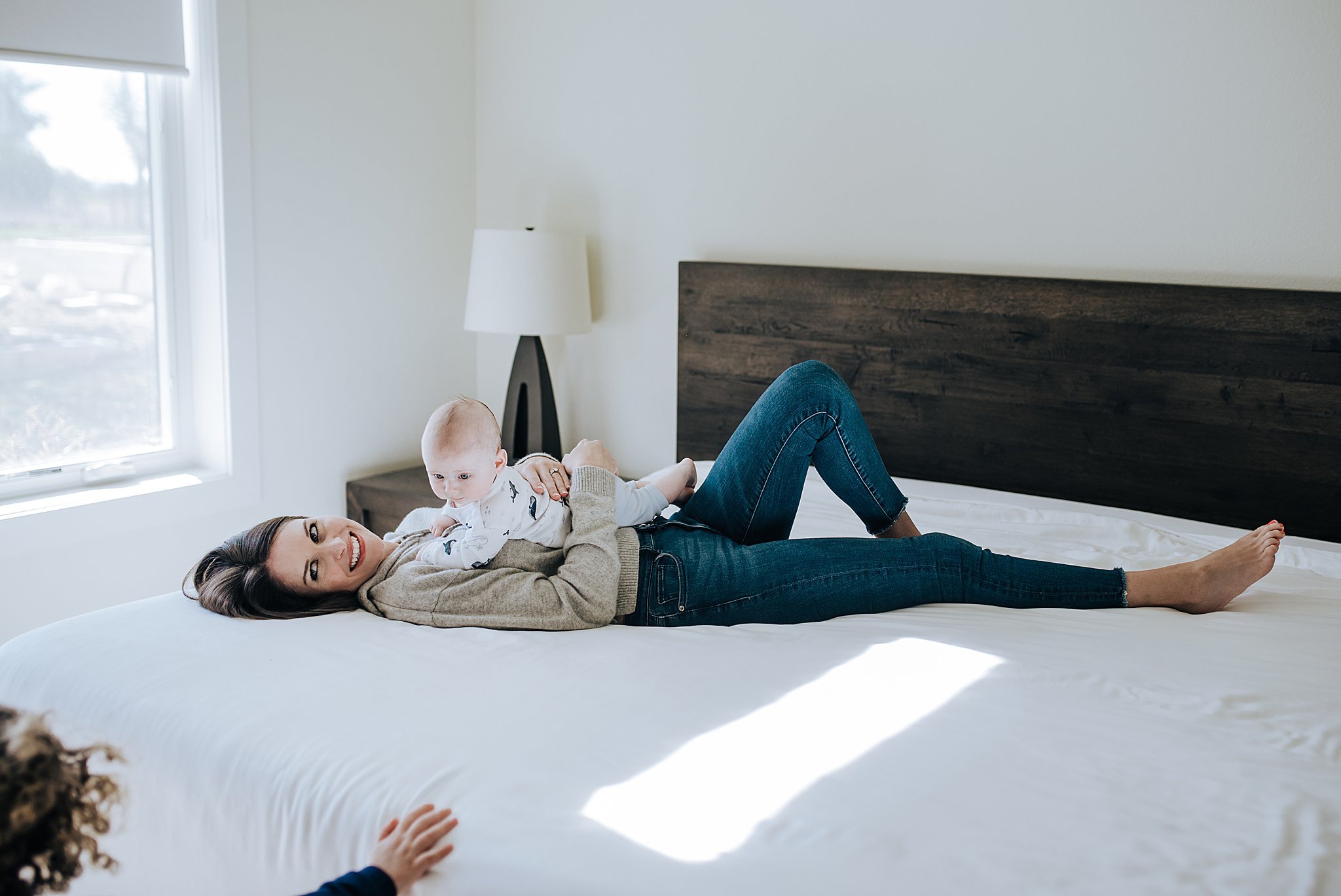 Stylish mom laying on her bed holding her newborn baby at her home in Red Rock Country Club, taken by Alyssa Charboneau Photography.