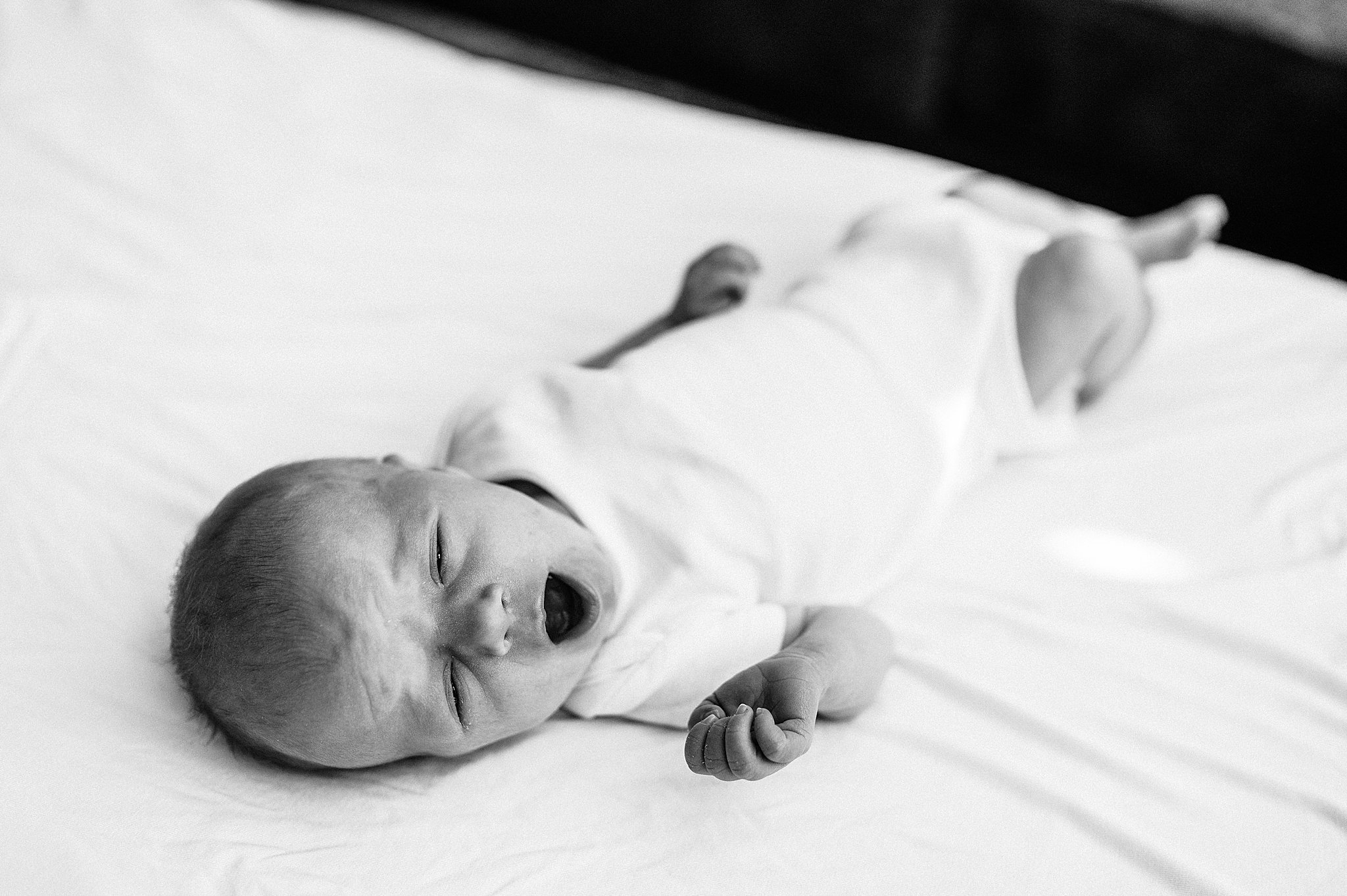 Black and white photo of a newborn baby yawning at his in-home newborn session, in Las Vegas, NV.