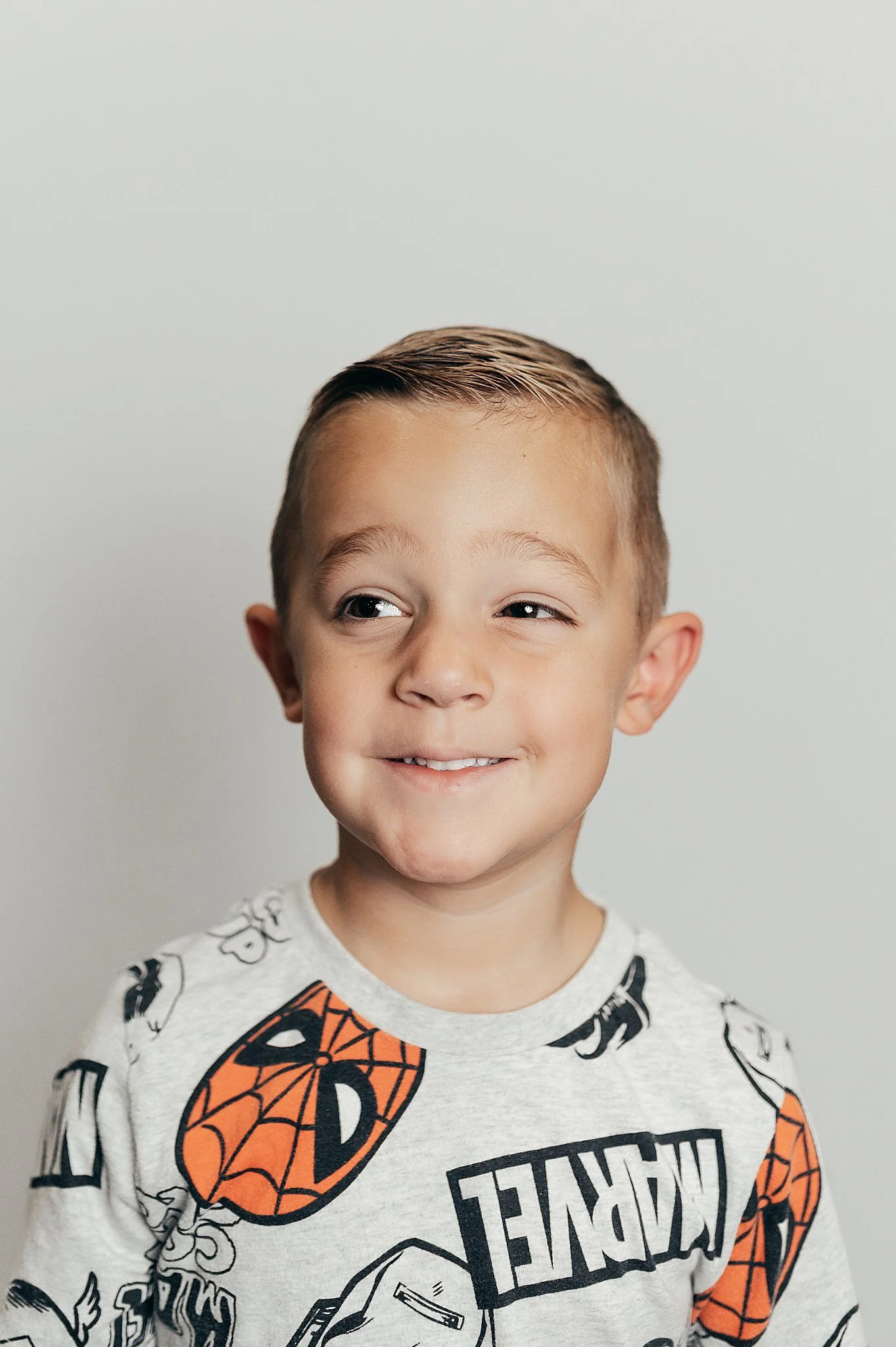 3rd grade boy in a marvel shirt smirking during his school portraits.