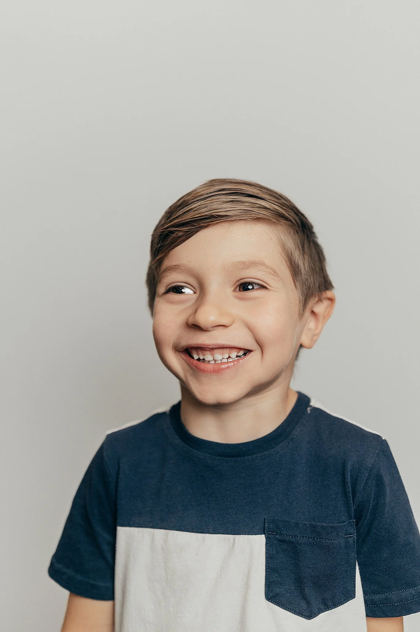 2nd grade boy in a blue and white shirt smiling for his school portrait.