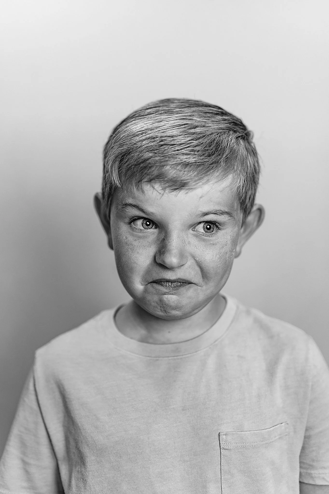 Black and white images of a 7 year old boy making a silly smile in his school picture.