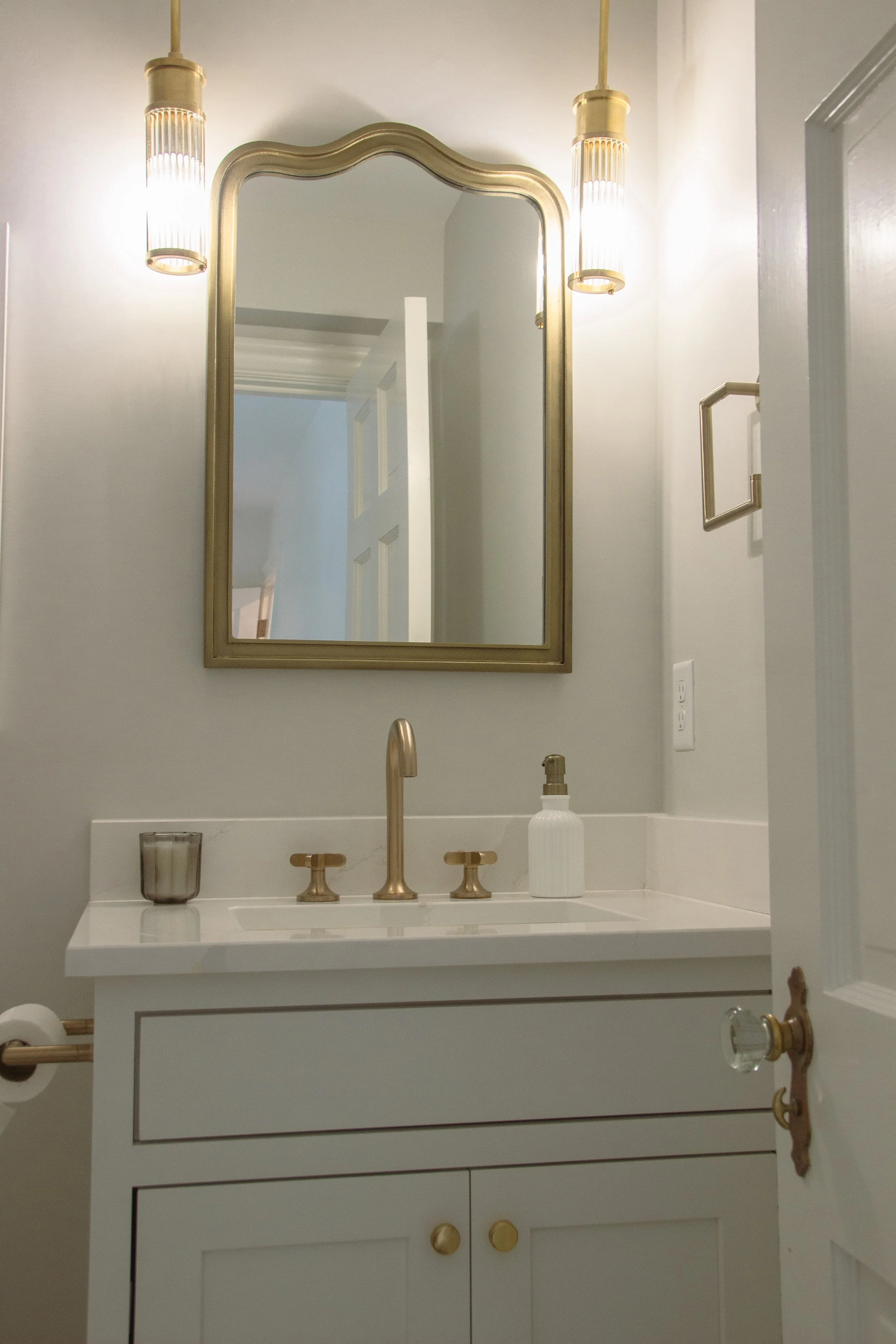 Bathroom vanity with brass fixtures, sculpted mirror, and balanced lighting, reflecting Studio Nine Interiors’ restrained and functional design approach.