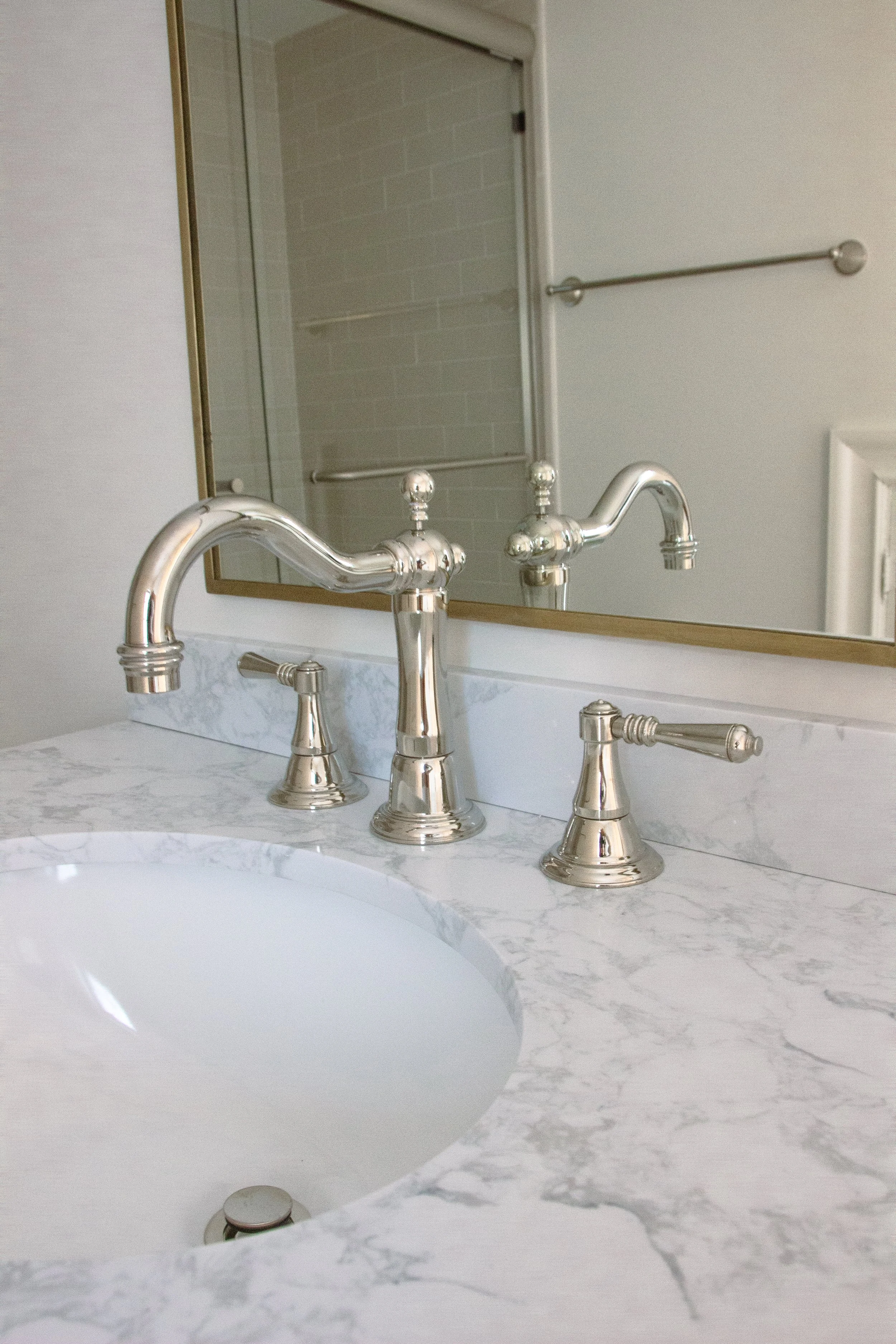 Polished stone countertop with integrated sink and classic metal faucet, showing subtle veining and a restrained edge profile.