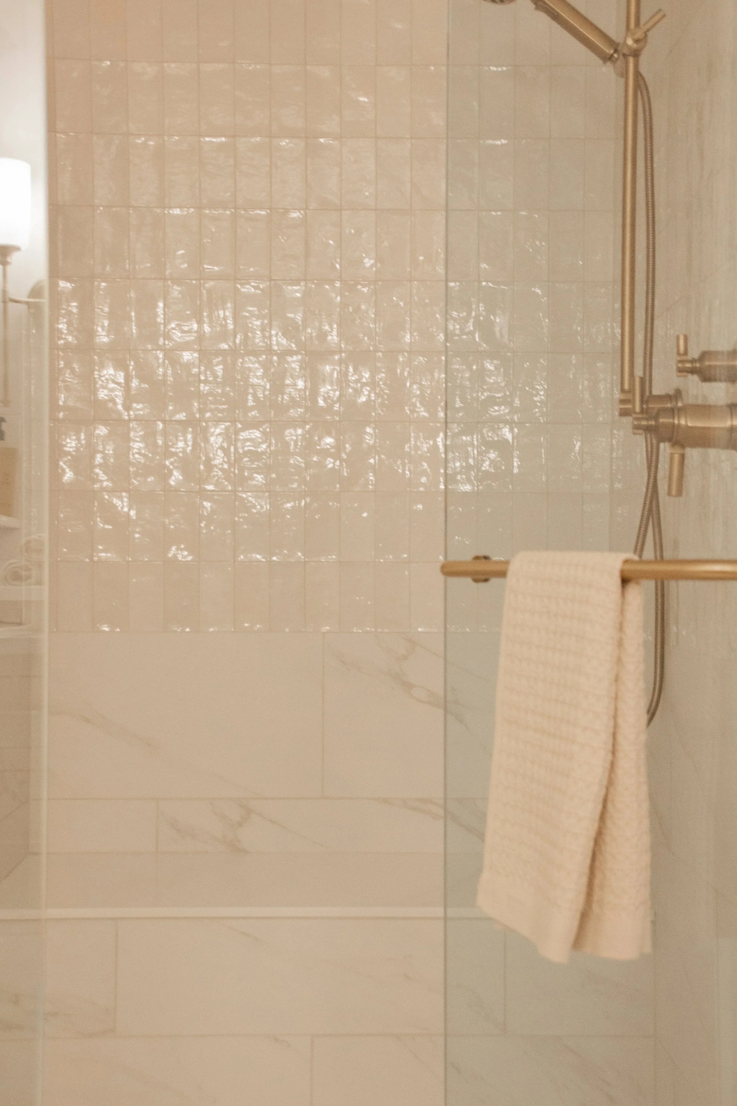 Walk-in shower with softly textured tile, glass enclosure, and warm metal fixtures designed for everyday use and comfort.