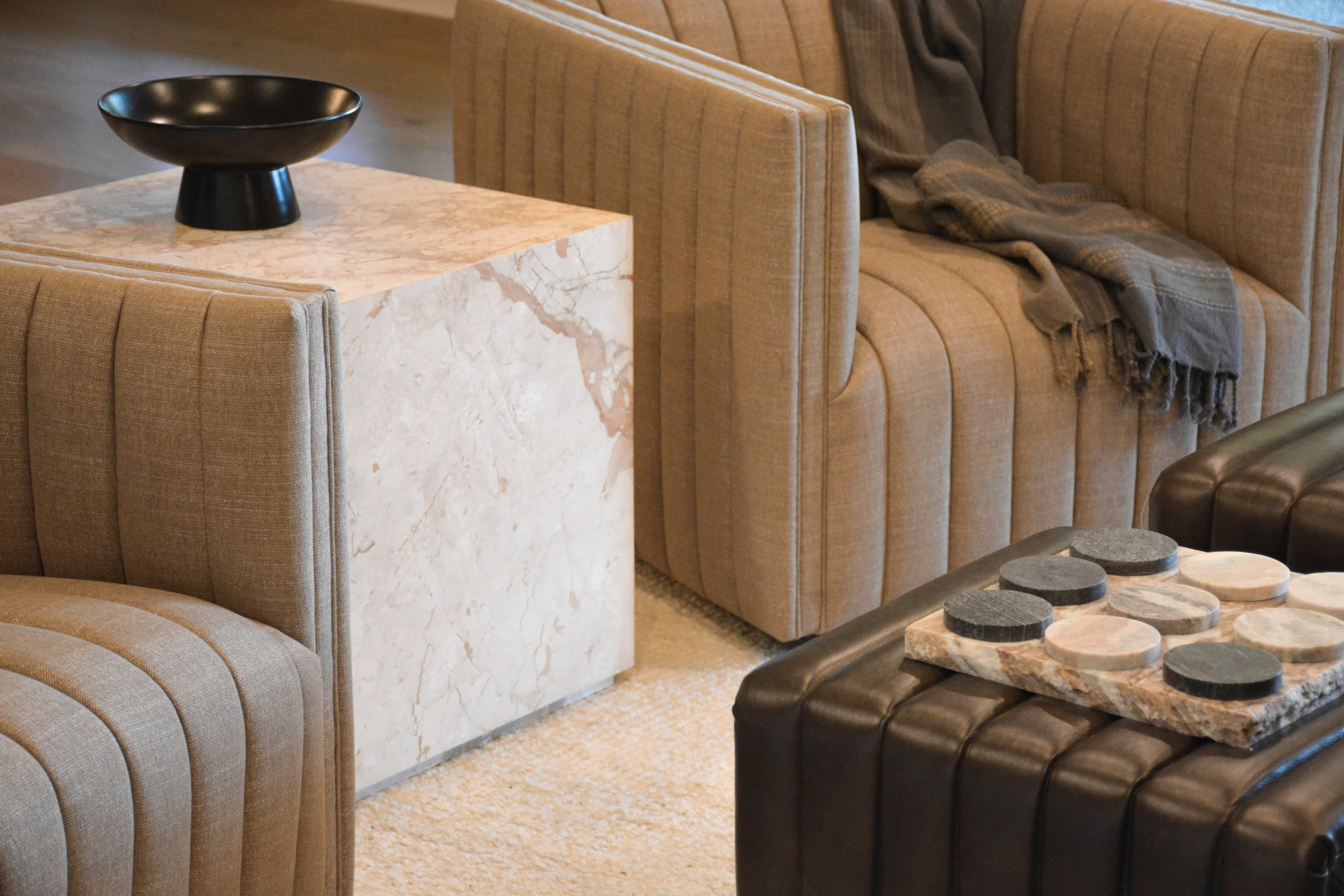 Textured lounge chairs, a marble accent table, and layered decorative accessories that demonstrate how fabrics and materials complement custom window treatments throughout a room.