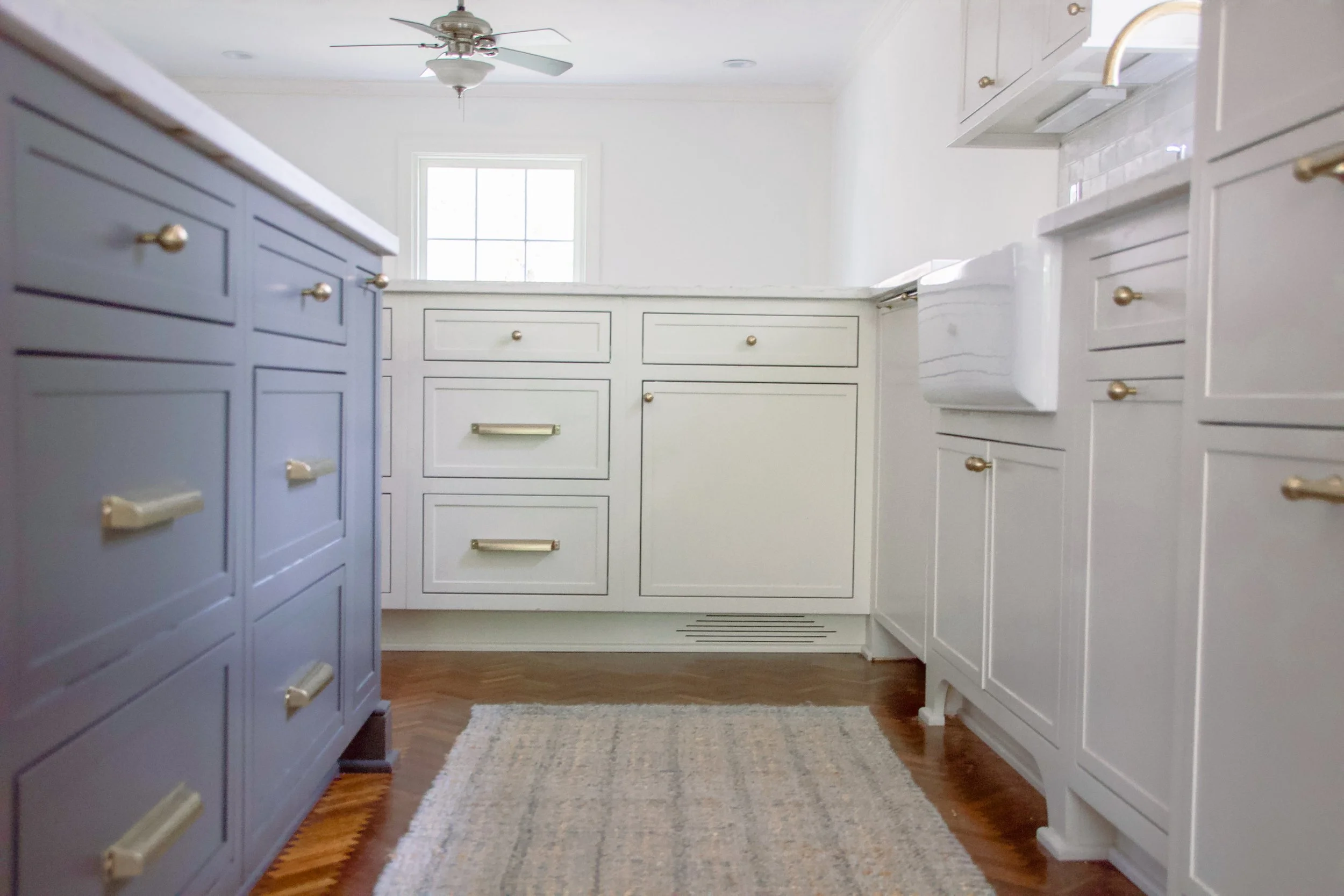Laundry room featuring custom cabinetry, brass hardware, a farmhouse sink, and generous storage designed as part of a full-scale home renovation.