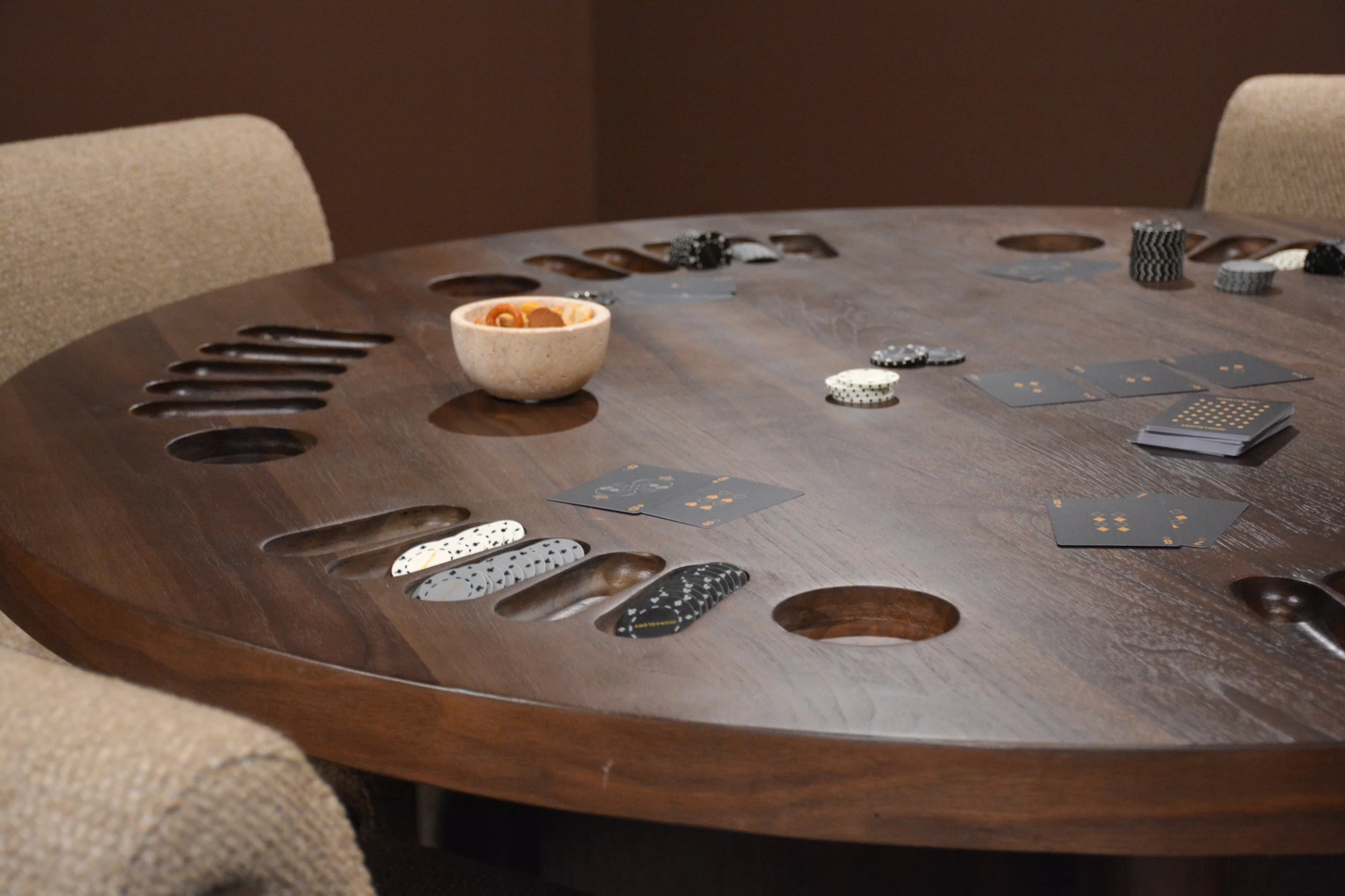 Custom round wood game table with built-in chip trays and card holders in a finished basement lounge.
