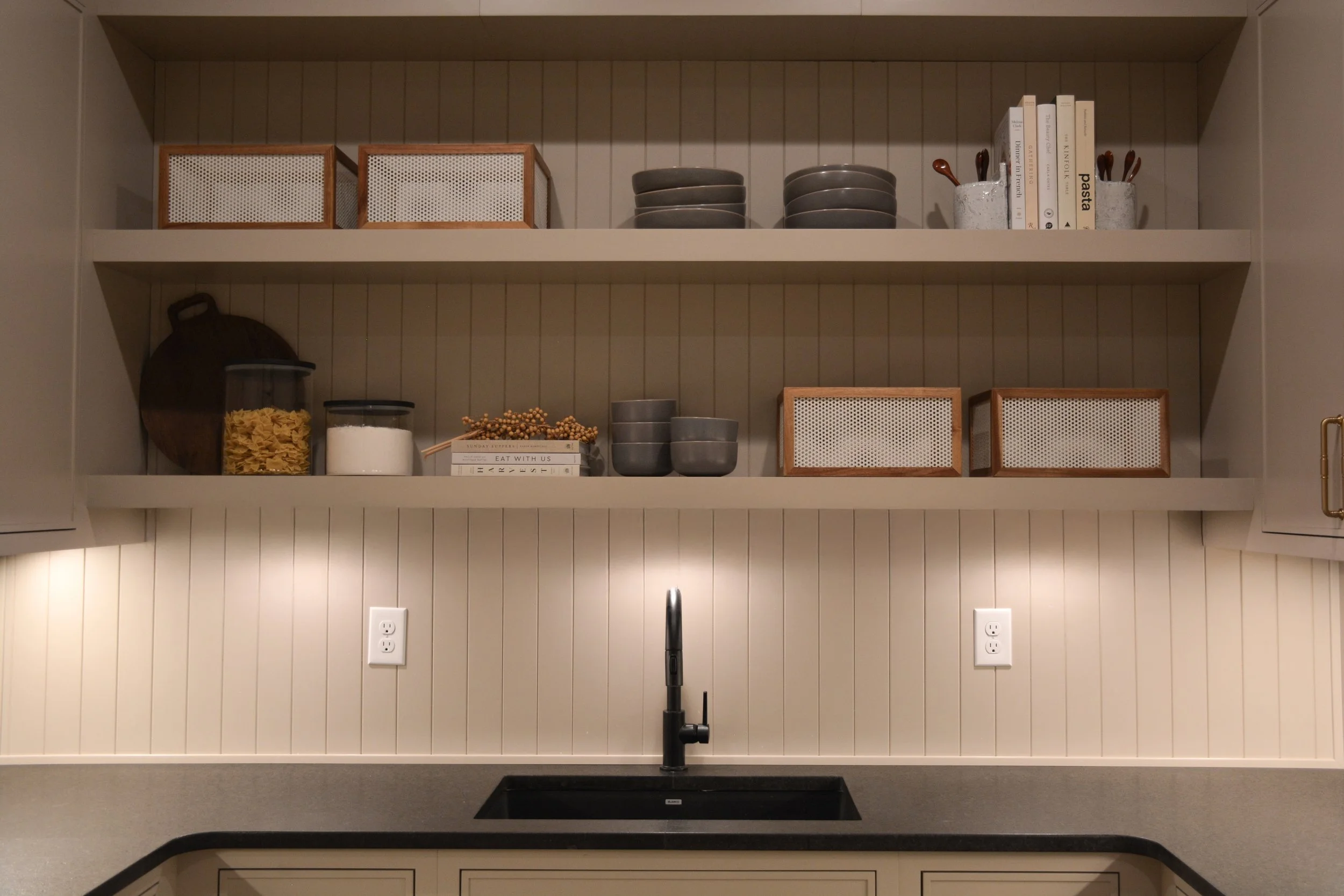 Custom pantry area featuring open shelving, integrated lighting, beadboard backing, and a prep sink designed as part of a full-scale home renovation.