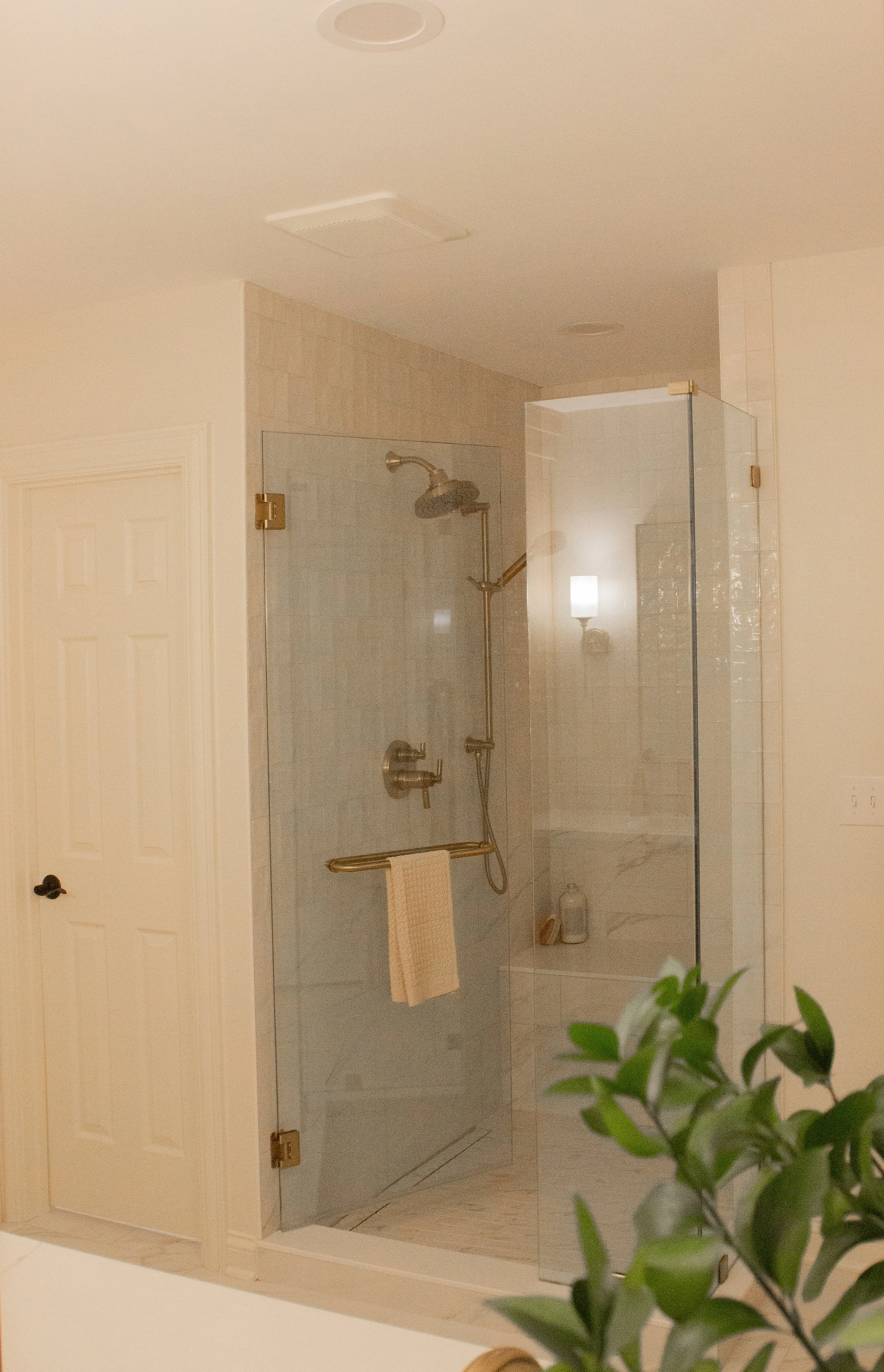 Glass-enclosed shower with light tile, warm metal fixtures, and clear sightlines supporting a focused, calm layout strategy.,
