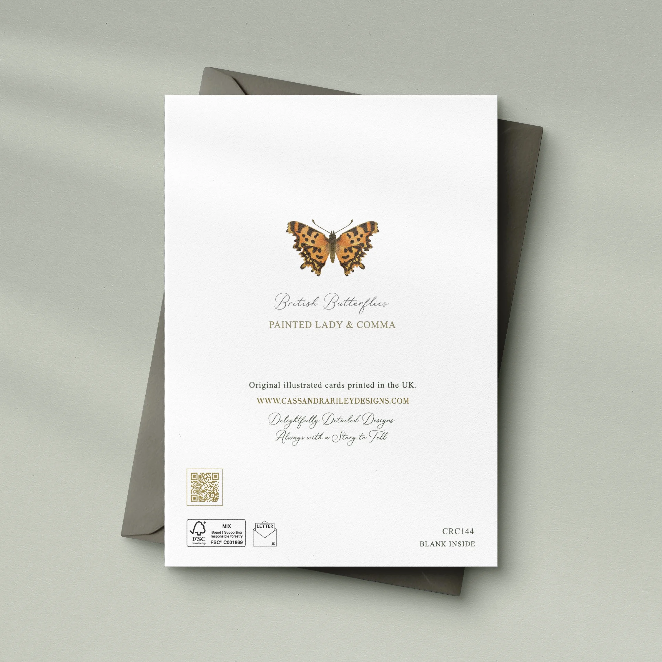 Greeting card with the details on the back and an illustration of a comma butterfly alongside text. A grey envelope sits underneath the card. On a light green background.