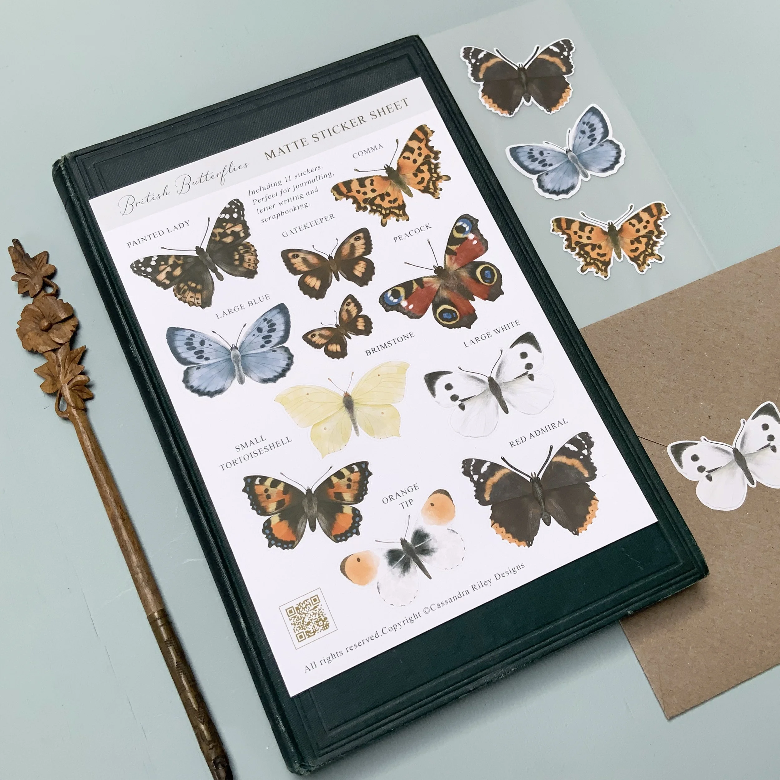 Sticker sheet with eleven different species of British Butterflies on. The sticker sheet sits on a vintage book.