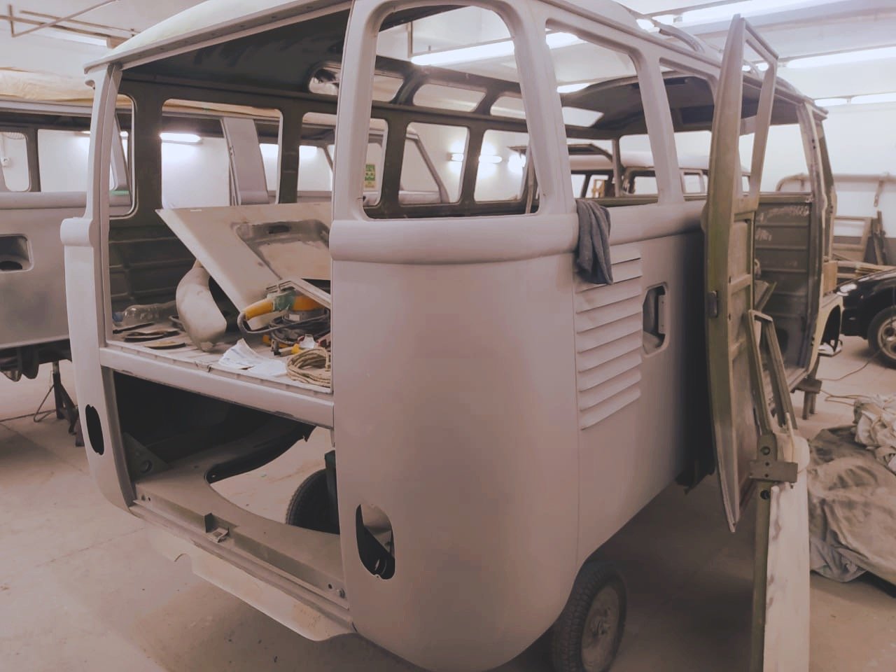 Unpainted vintage Volkswagen van in a workshop, partially disassembled for restoration