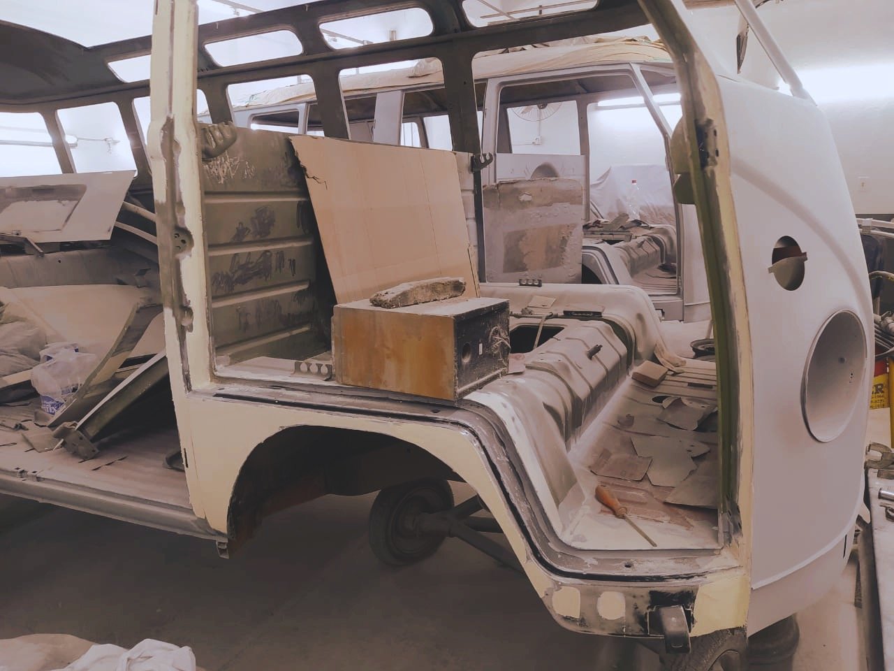 Partially restored vintage van interior under renovation with exposed metal framework and tools.