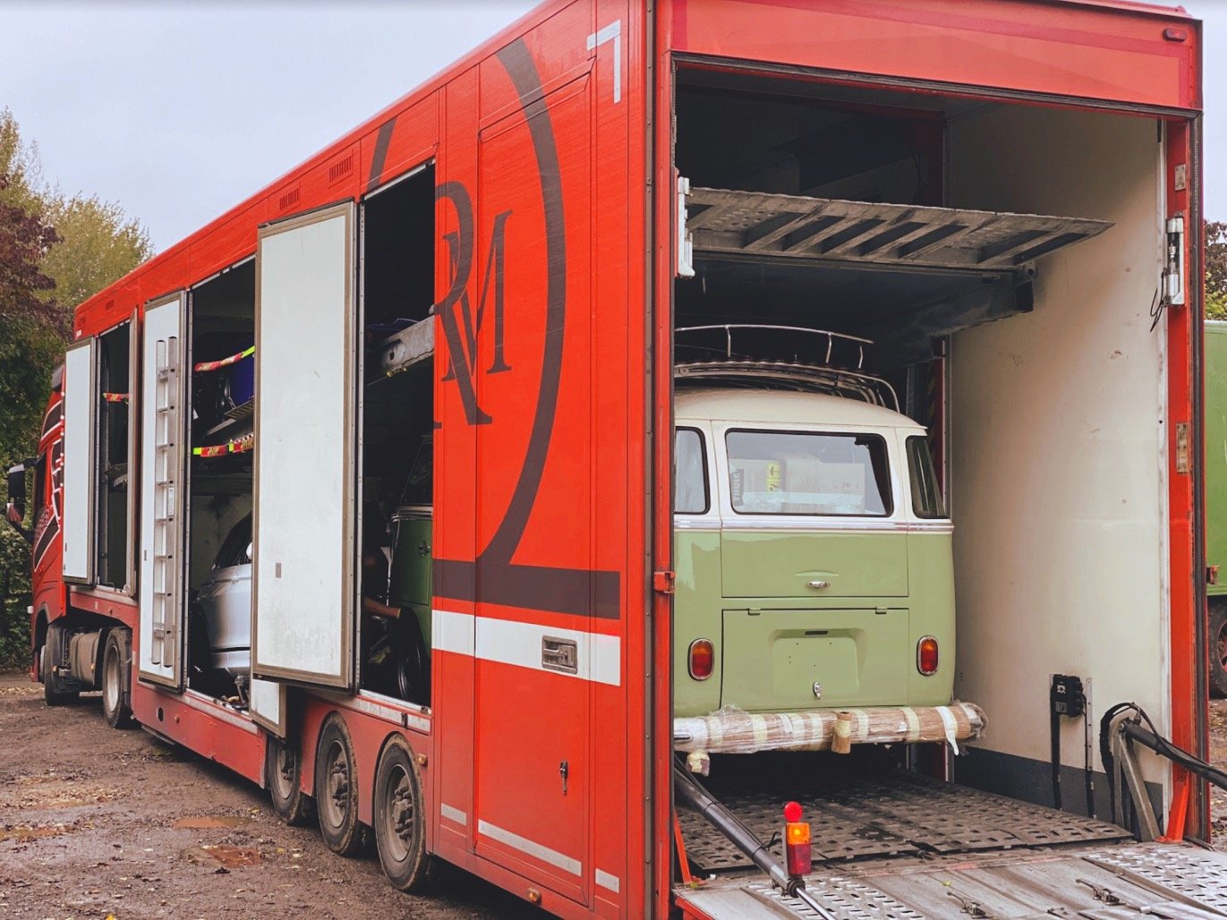 Red transport trailer with a green vintage van inside