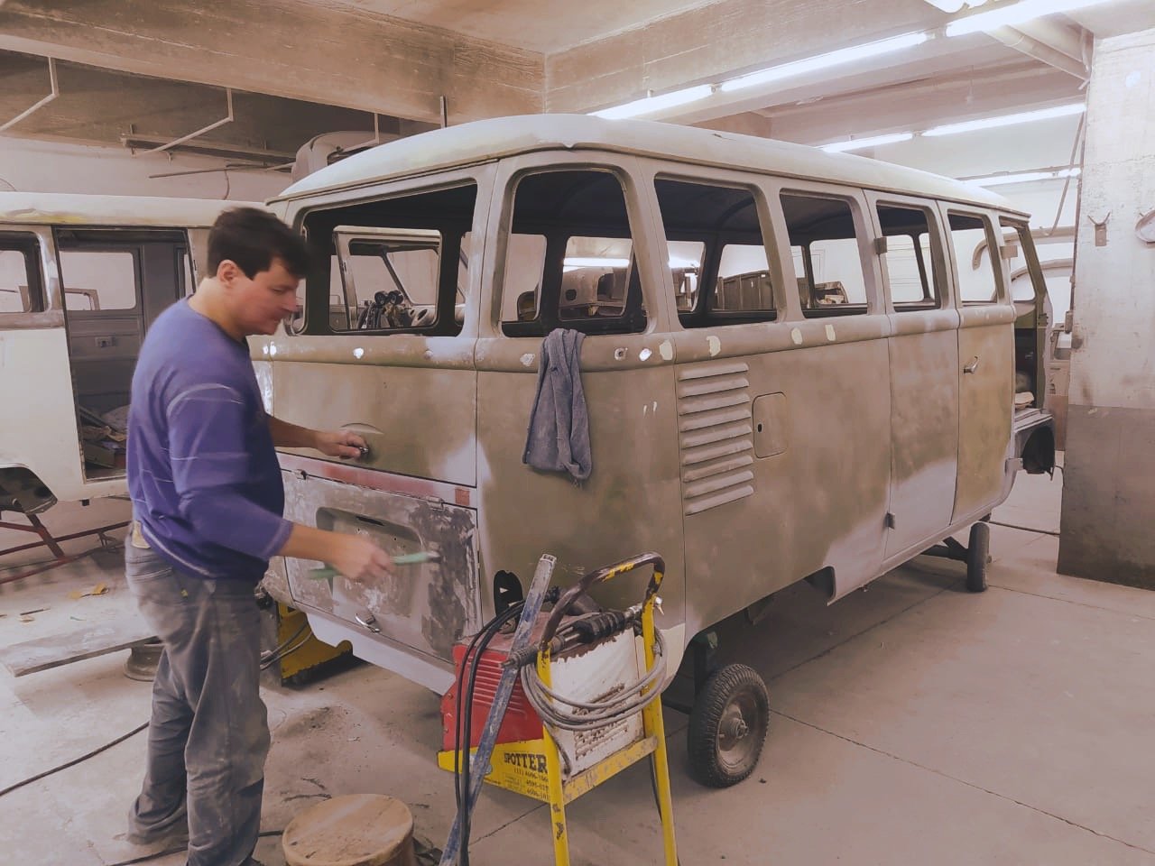 Man sanding a vintage van in a workshop for restoration