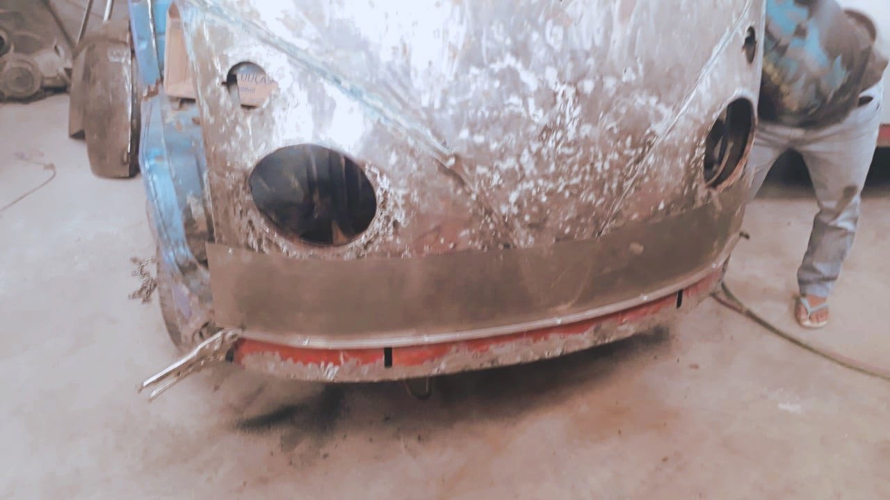 Rusty vintage car undergoing restoration in a workshop.