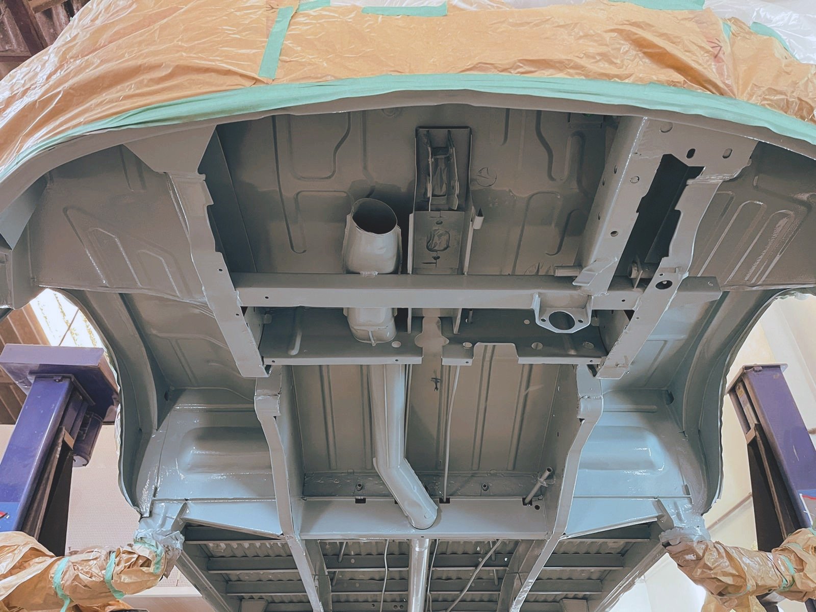 View of a car chassis on a lift, showing the underside with structural components and exhaust system.