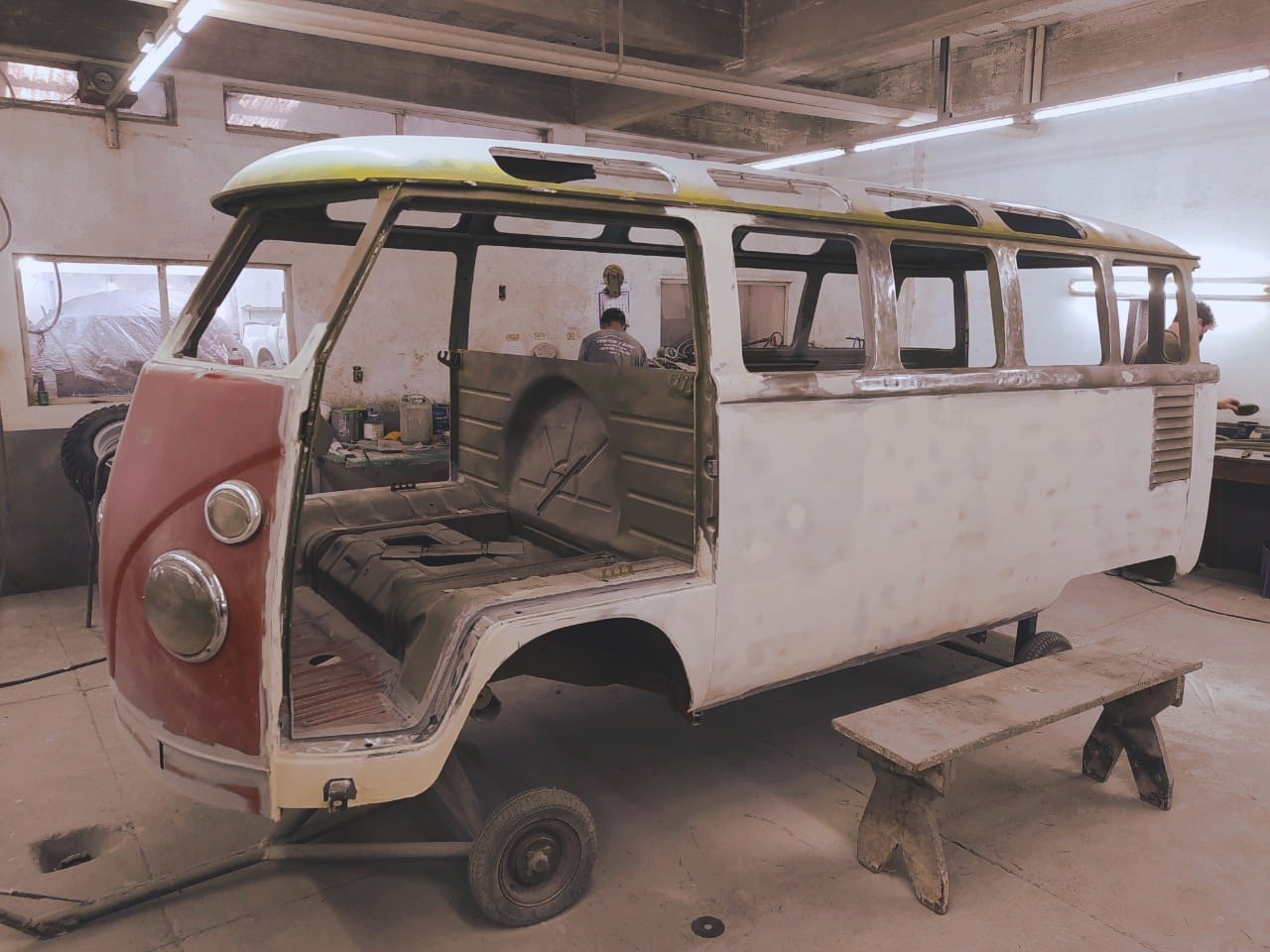 Partially restored vintage Volkswagen van in a workshop, with sanded exterior and missing parts.