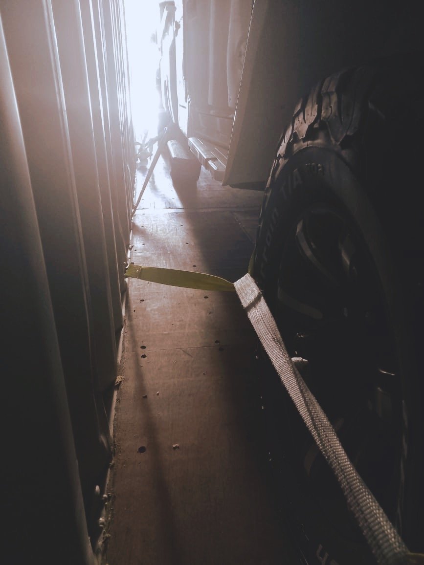 close-up of a vehicle tire inside a dimly lit storage space secured with a strap