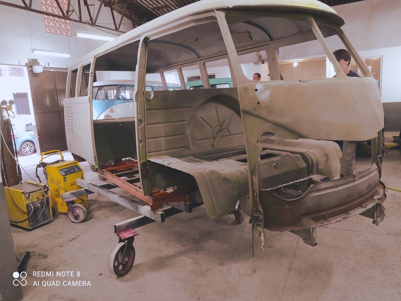 Vehicle restoration process in workshop with partially disassembled Volkswagen Bus.