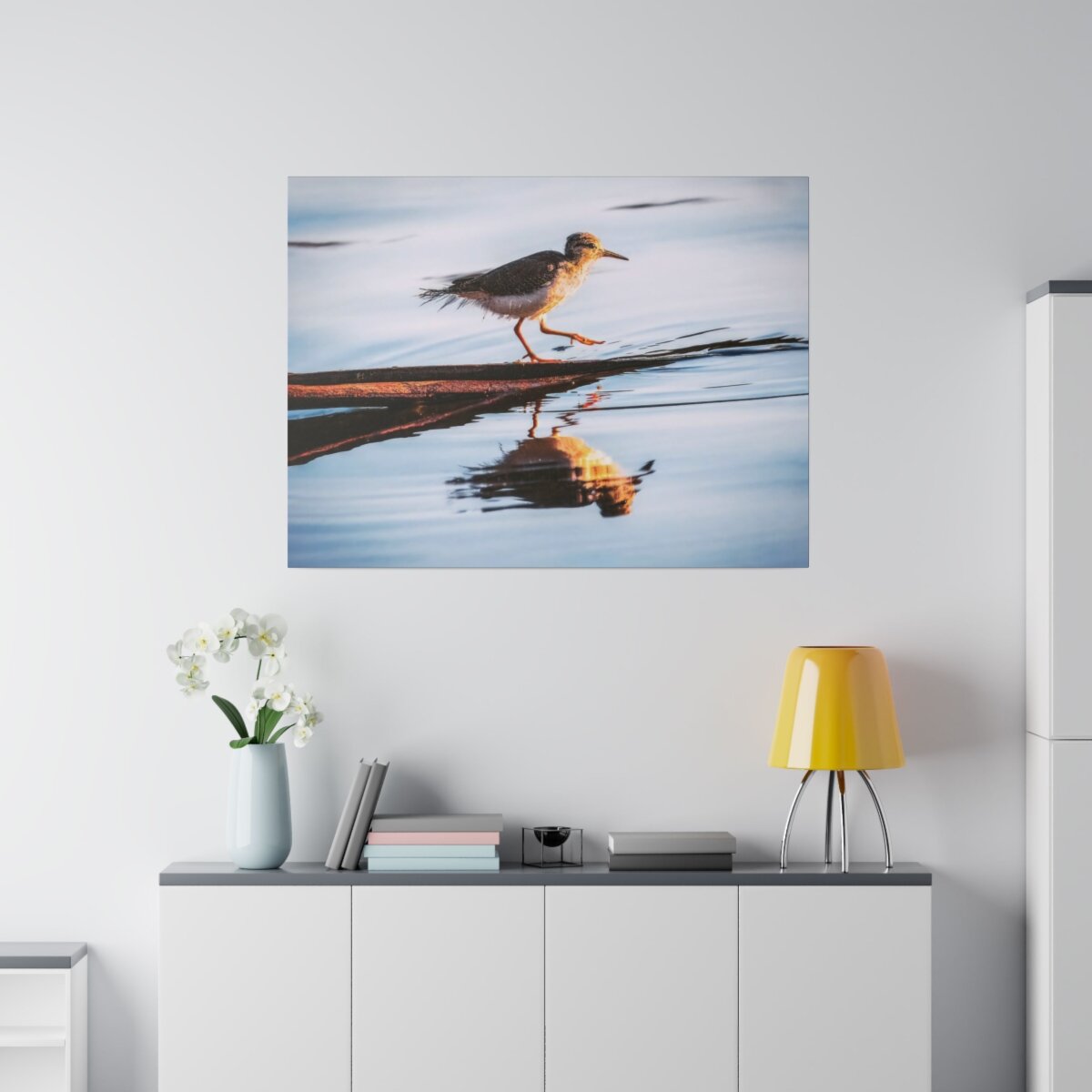 Frontal view of 'Serene Sandpiper Reflection' Canvas Print, showcasing a sandpiper bird gracefully striding on a log within a calm Canadian lake.
