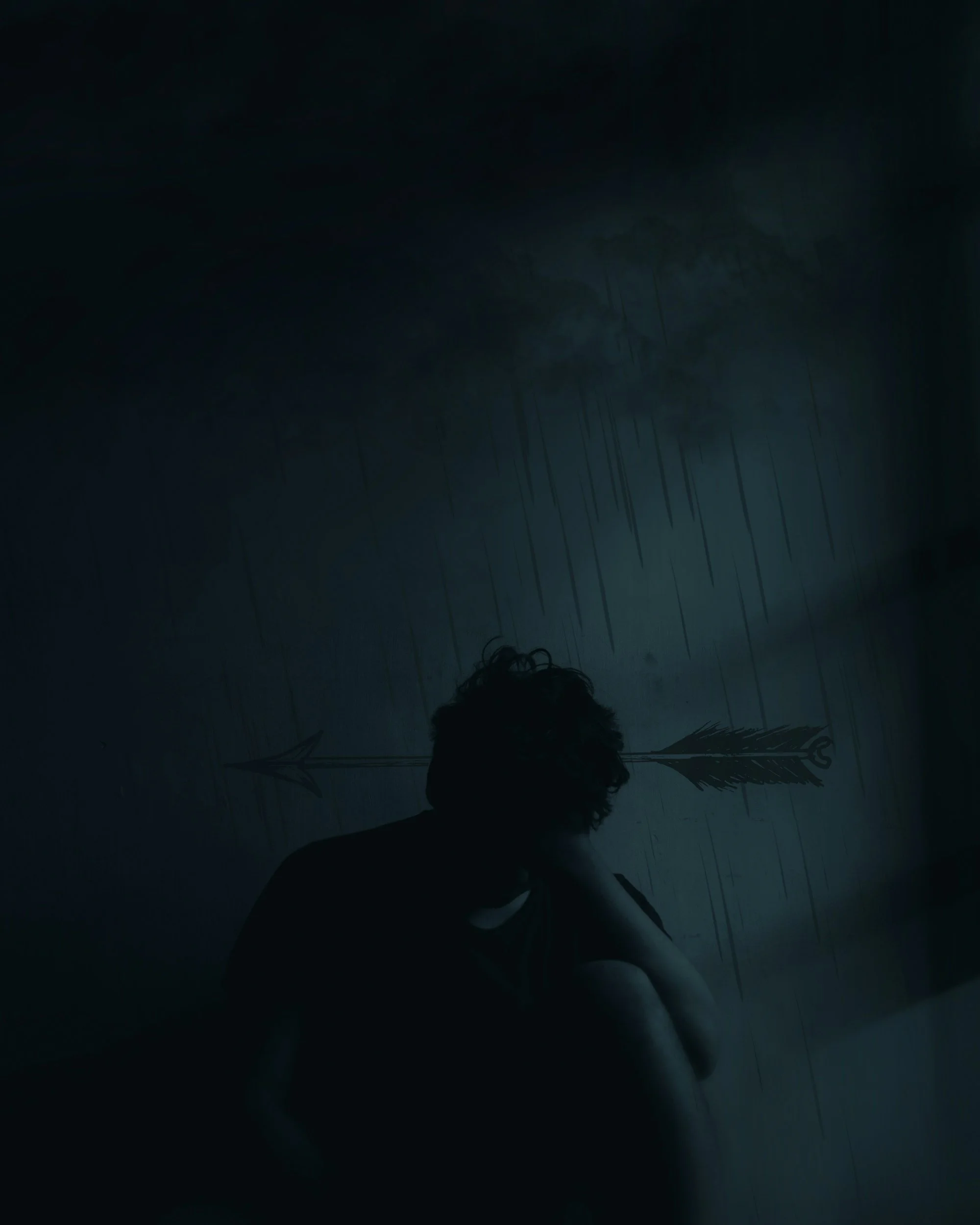 A silhouette of a person with curly hair is seen in a dark, rainy environment. The person is holding a bow and arrow, pointed horizontally. It is nighttime, and rain is falling heavily, creating a somber and intense atmosphere.