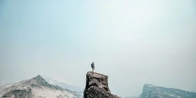 Man standing at the summit of a mountain.