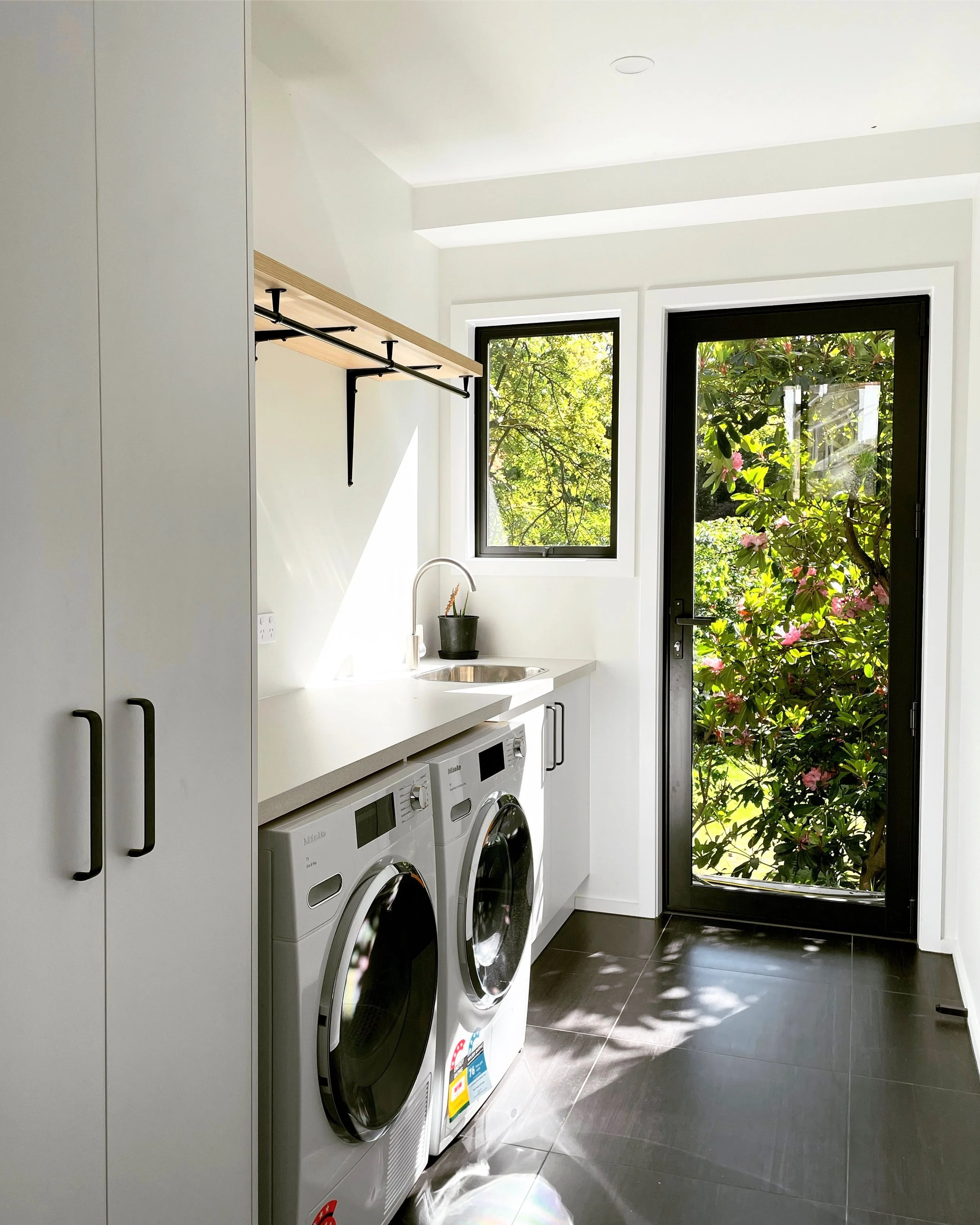 Overview of laundry with black accents and white cabinetry