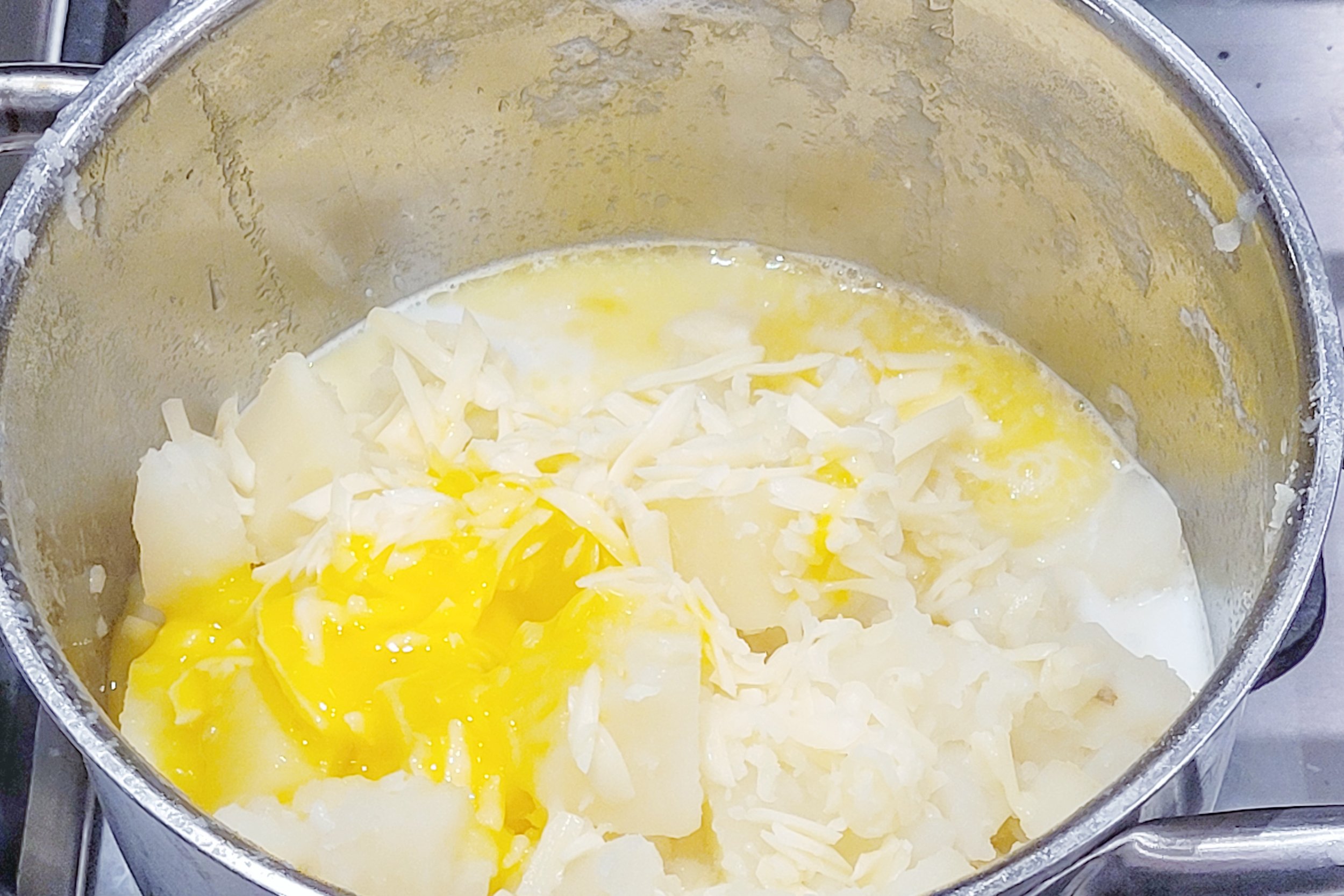 Drain water from potatoes. Add grated cheese, butter, milk to the empty potato pot. Pour in the potatoes, then add the egg yolks and mash everything together.