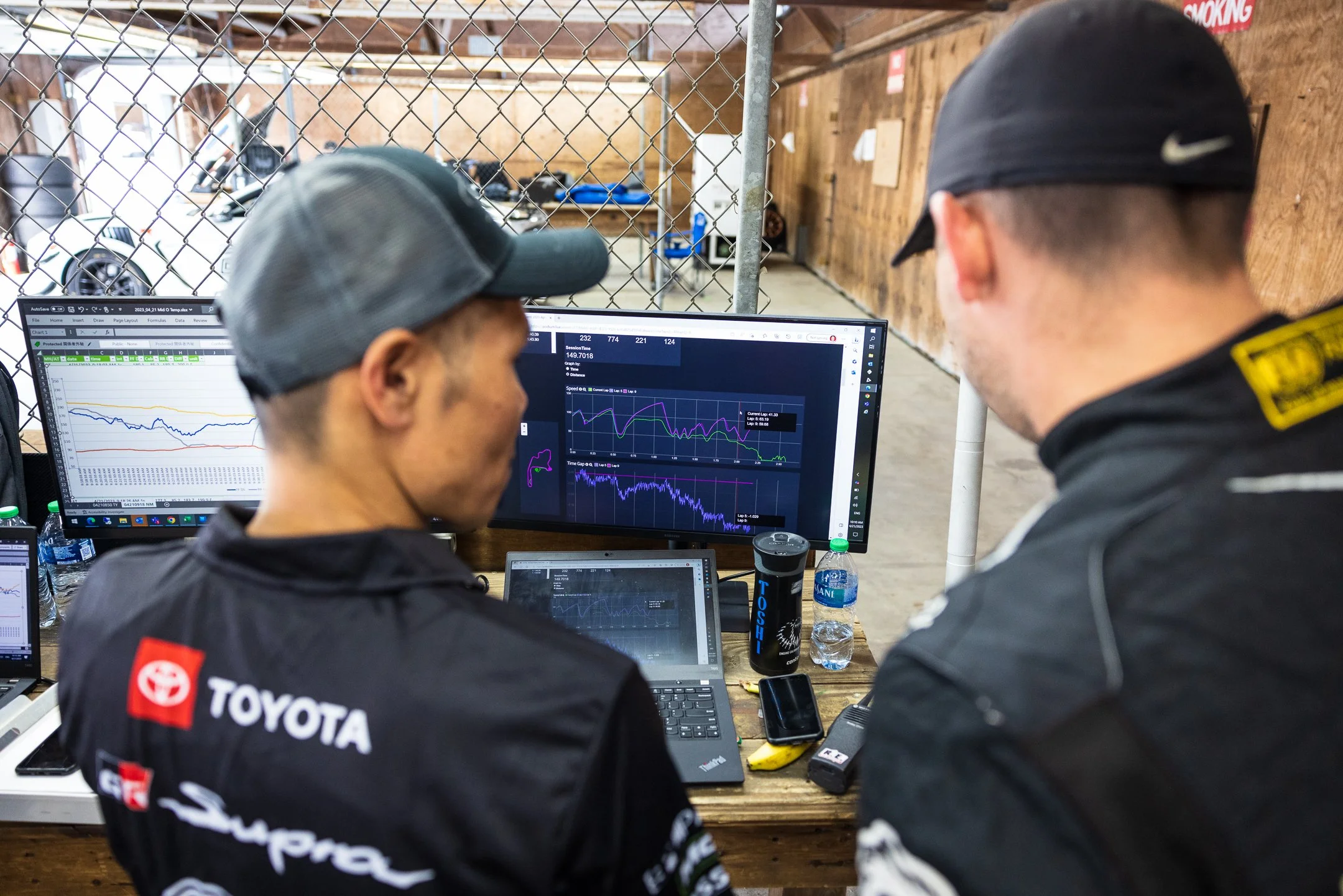 Toyota R&D Racing team members reviewing A90 Supra telemetry traces on monitors in the Mid-Ohio garage.