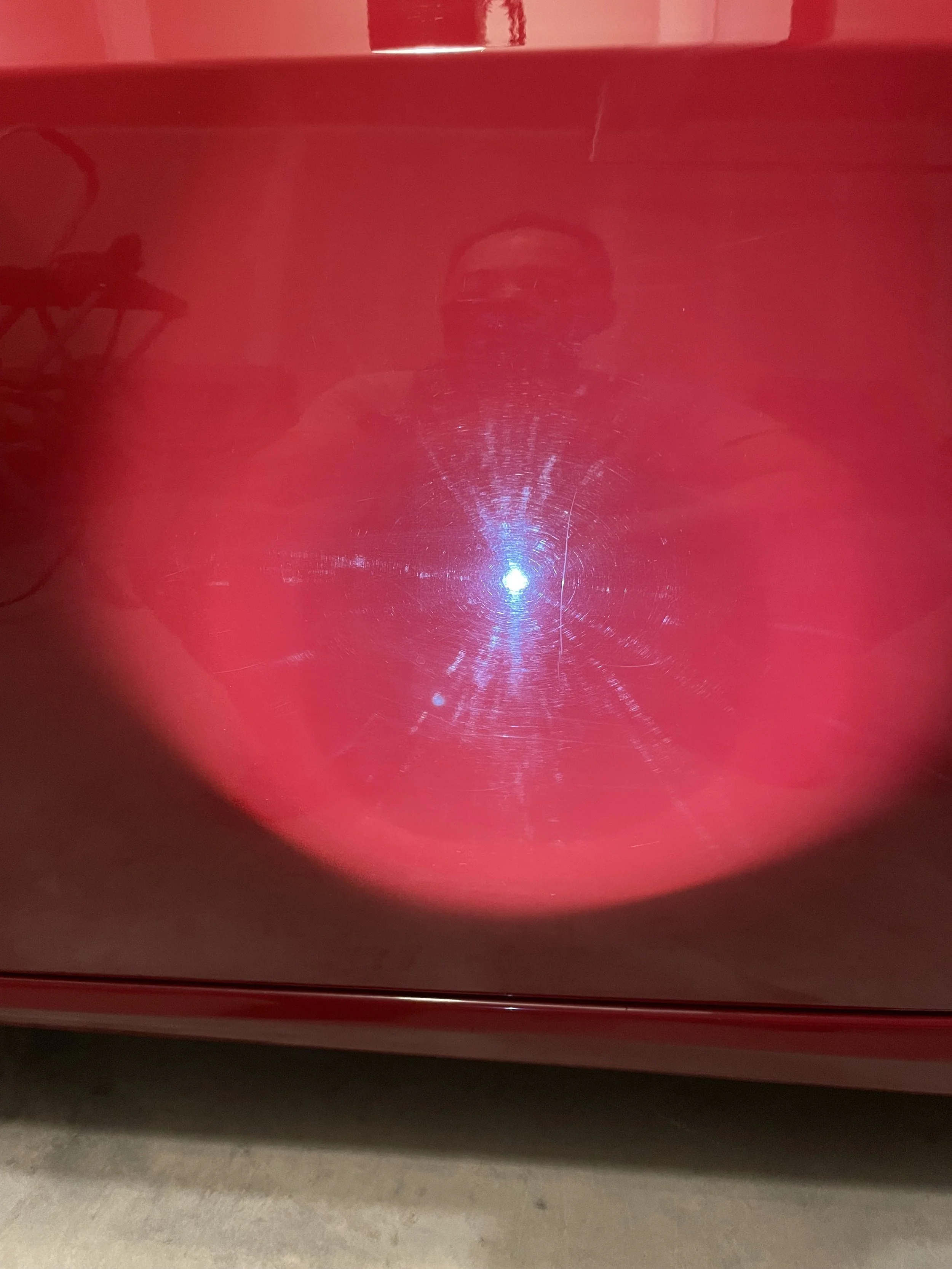 Swirl marks around a bright light reflection in the red FR-S bodywork.