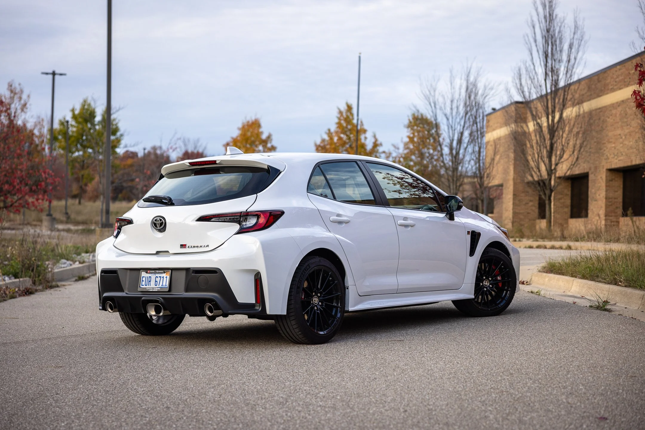 White 2024 Toyota GR Corolla photo in front of tan brick building in autumn