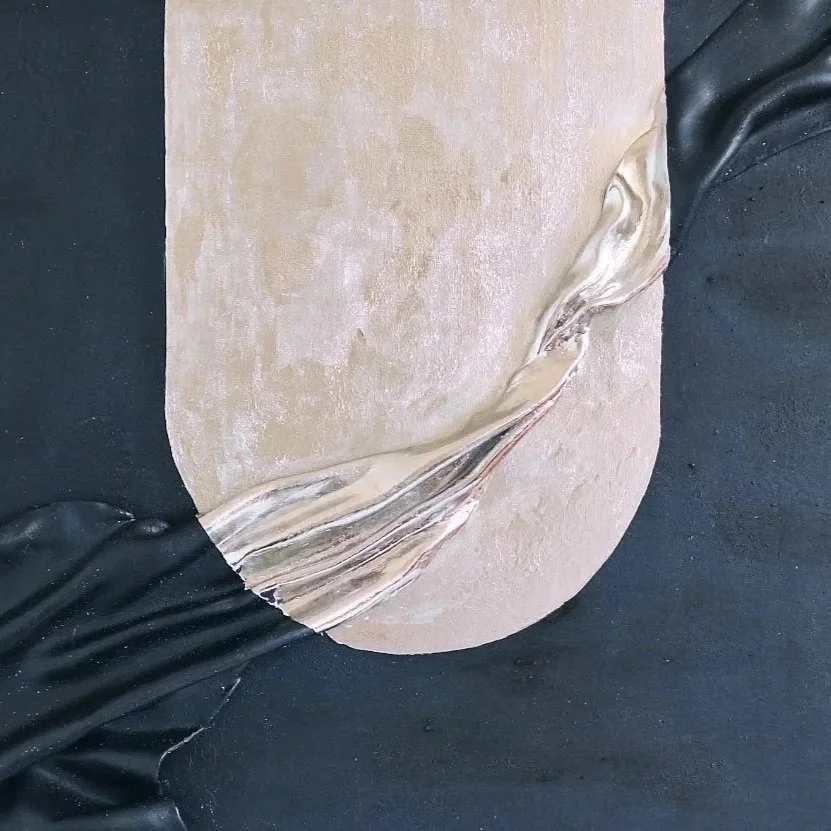 A close-up of a larger painting that looks abstractedly like the moon falling through the night sky on a dark surface.