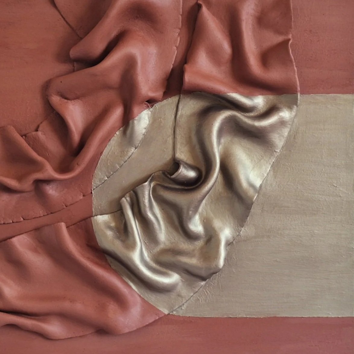 Close-up of a mixed-material textured artwork using attached fabric and metallic-looking sections, with brown and beige tones.