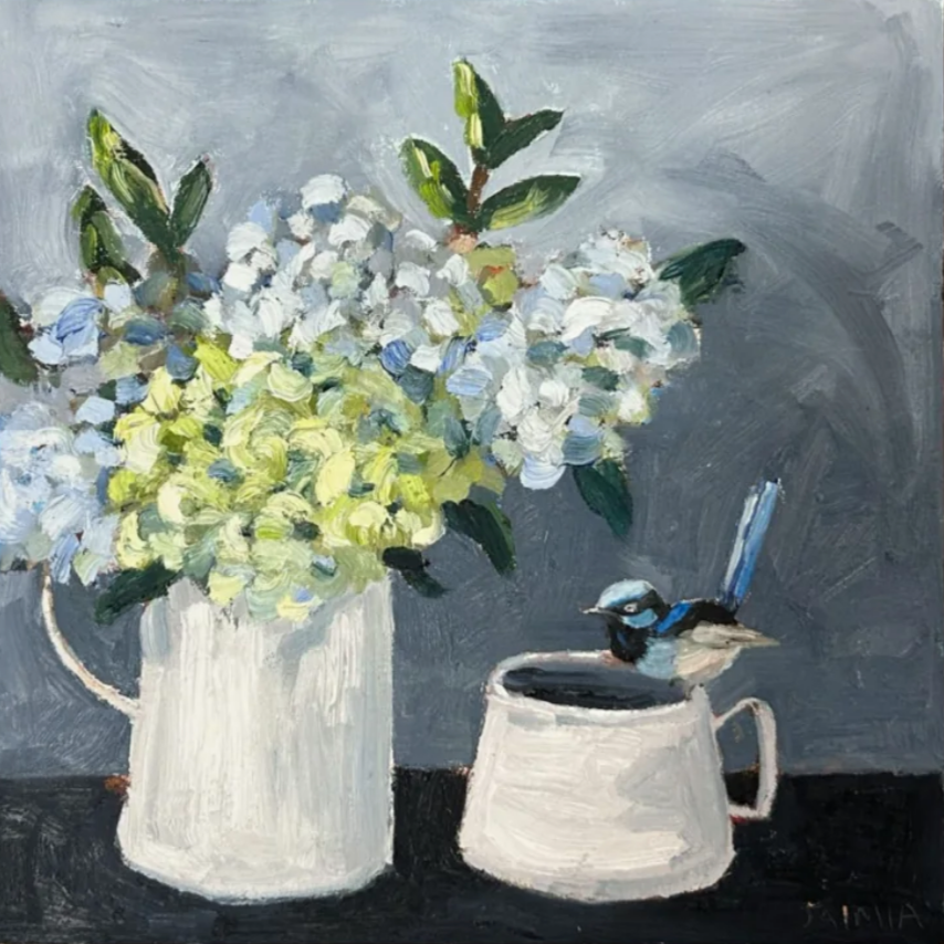 A still life painting of a white vase filled with white and pale blue flowers, and a white mug with a blue fairy wren perched on top, on a dark surface against a grey background.