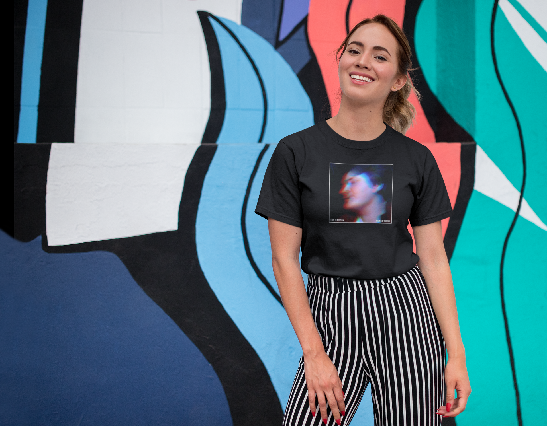 tee-mockup-of-a-smiling-girl-in-front-of-a-wall-with-colorful-illustrations-26646.png